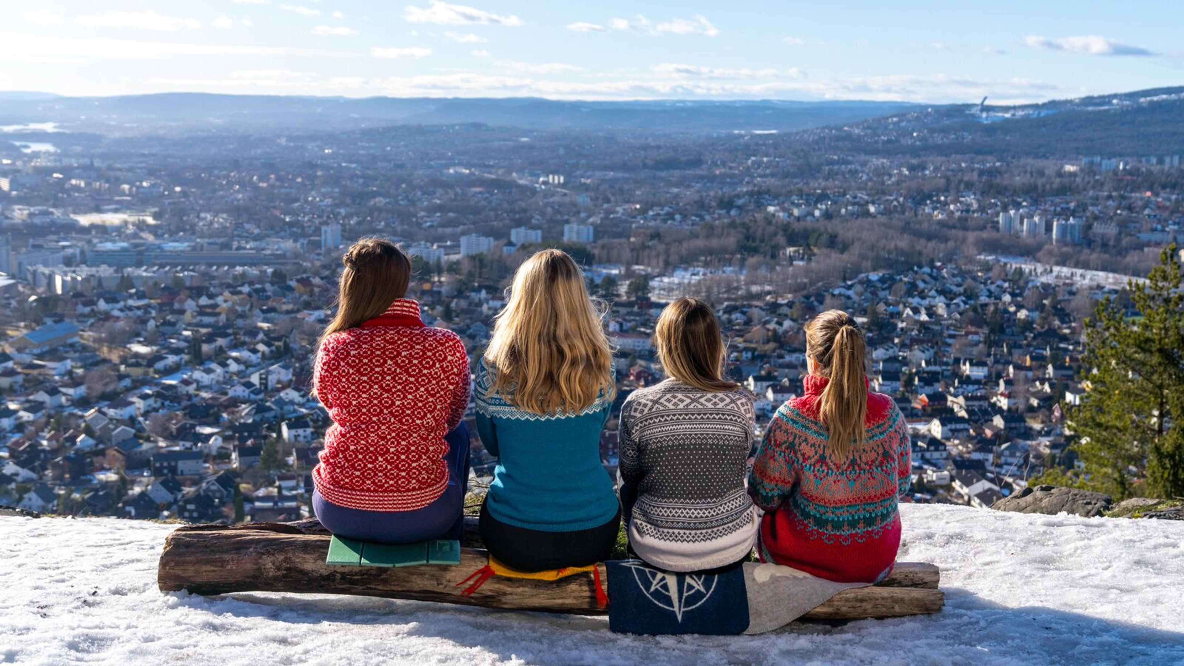 Women sit and watch the view of Oslo in knitted overalls, Norway.