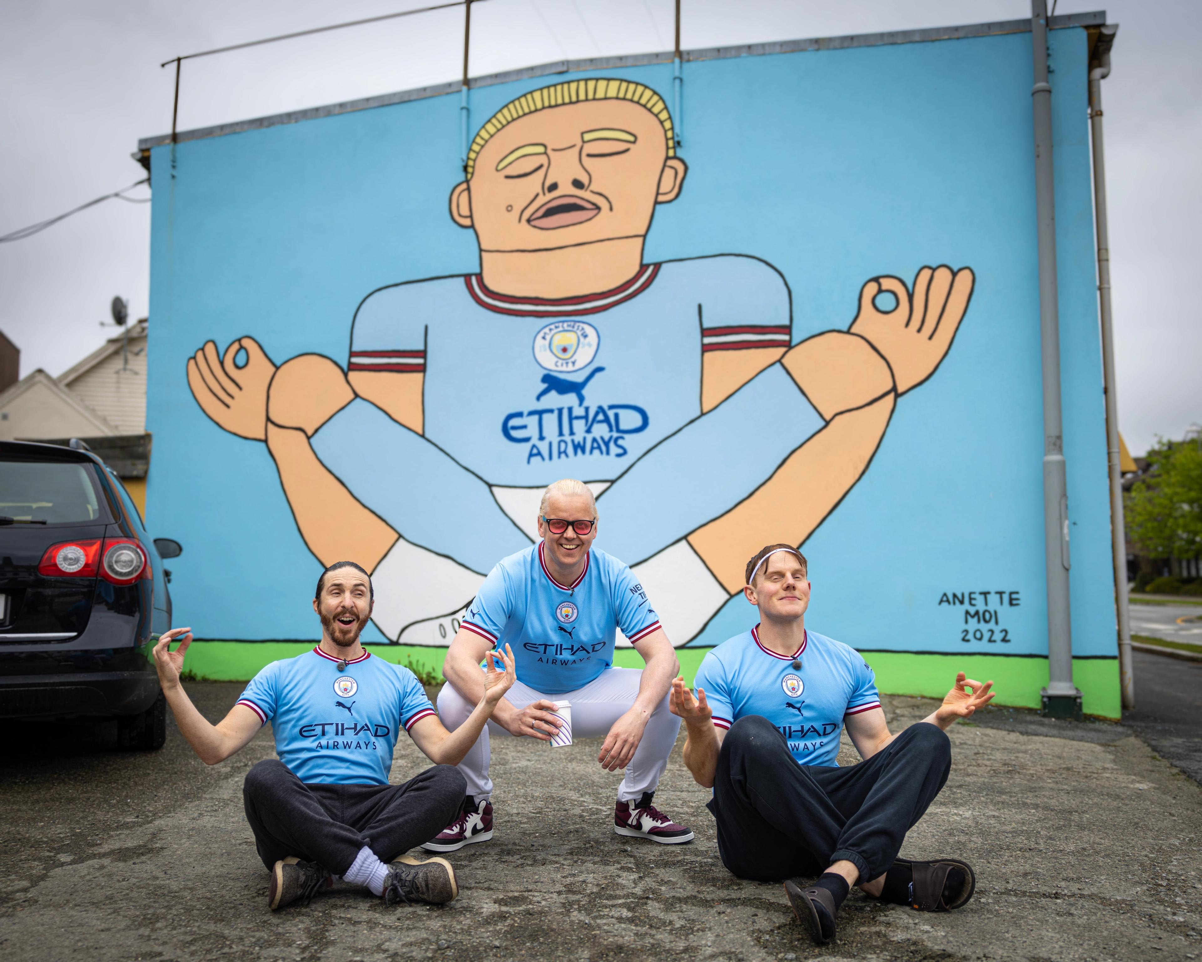 Three men in front of the Erling Braut Haaland street art by Anette Moi in Bryne, Fjord Norway