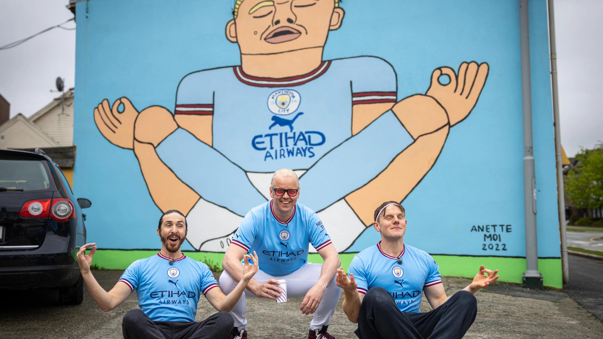 Three men in front of the Erling Braut Haaland street art by Anette Moi in Bryne, Fjord Norway