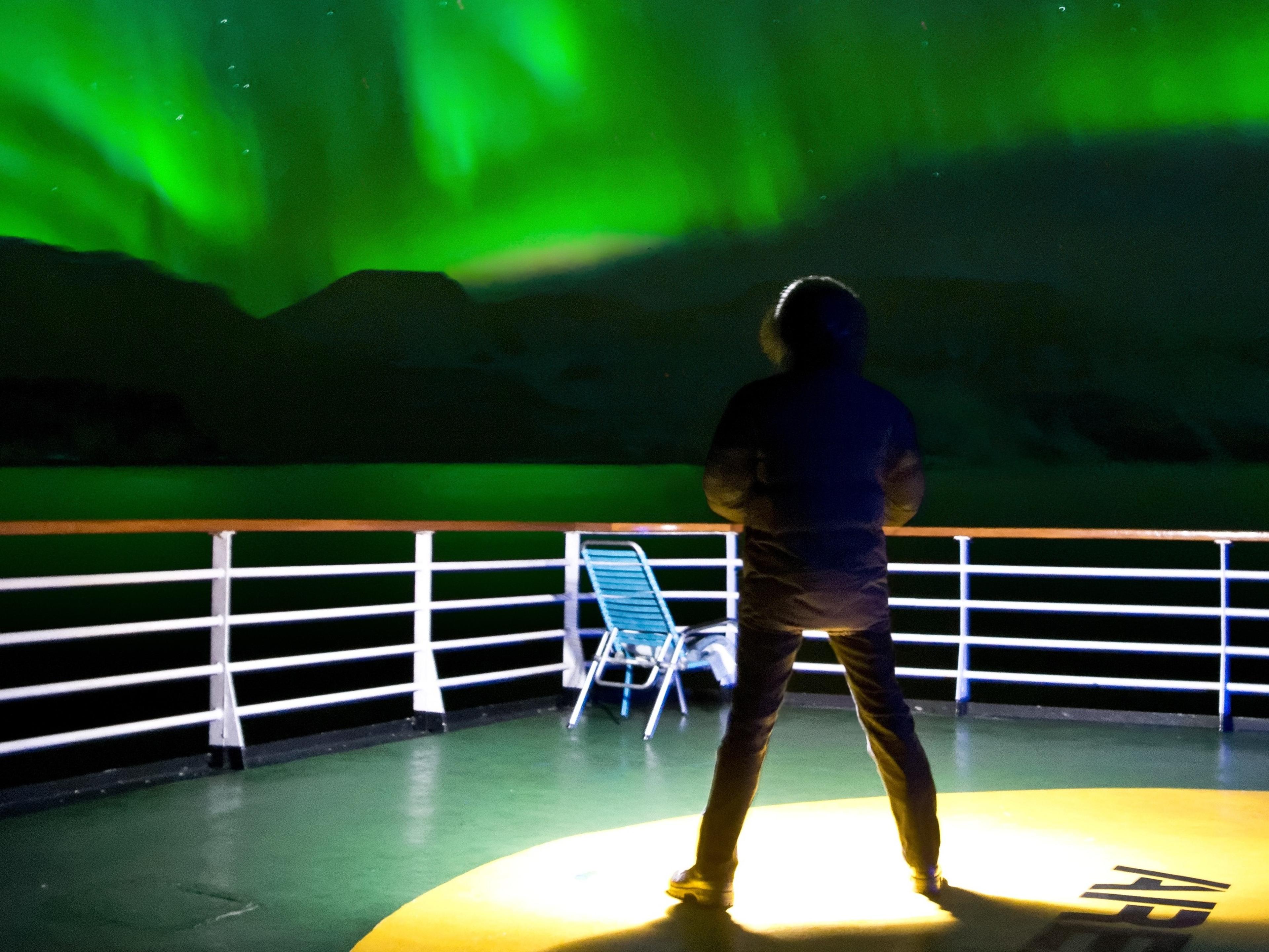 Man standing on deck looking at the northern lights