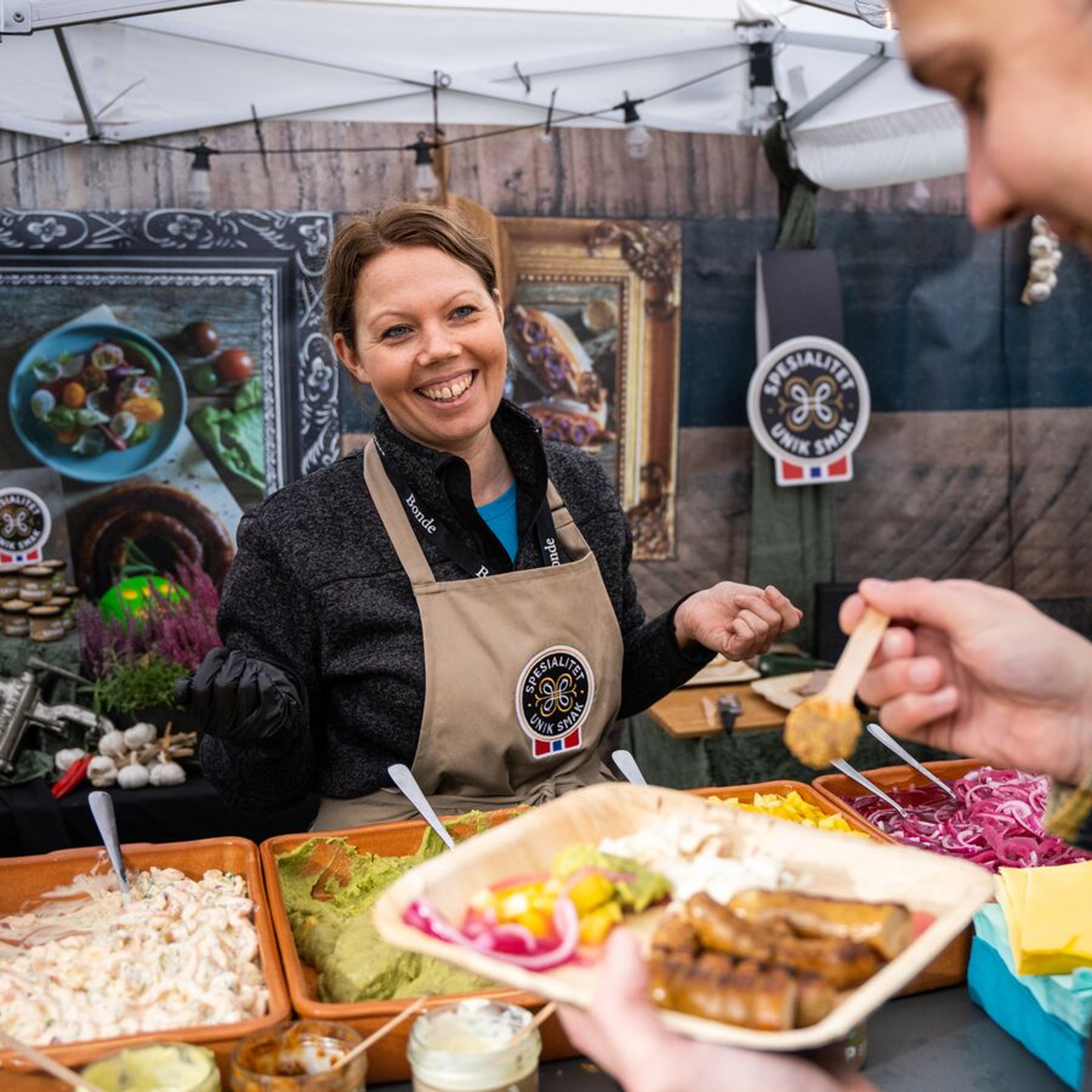 En mann spiser en servering med forskjellige pølser på Matstreif matfestival i Oslo
