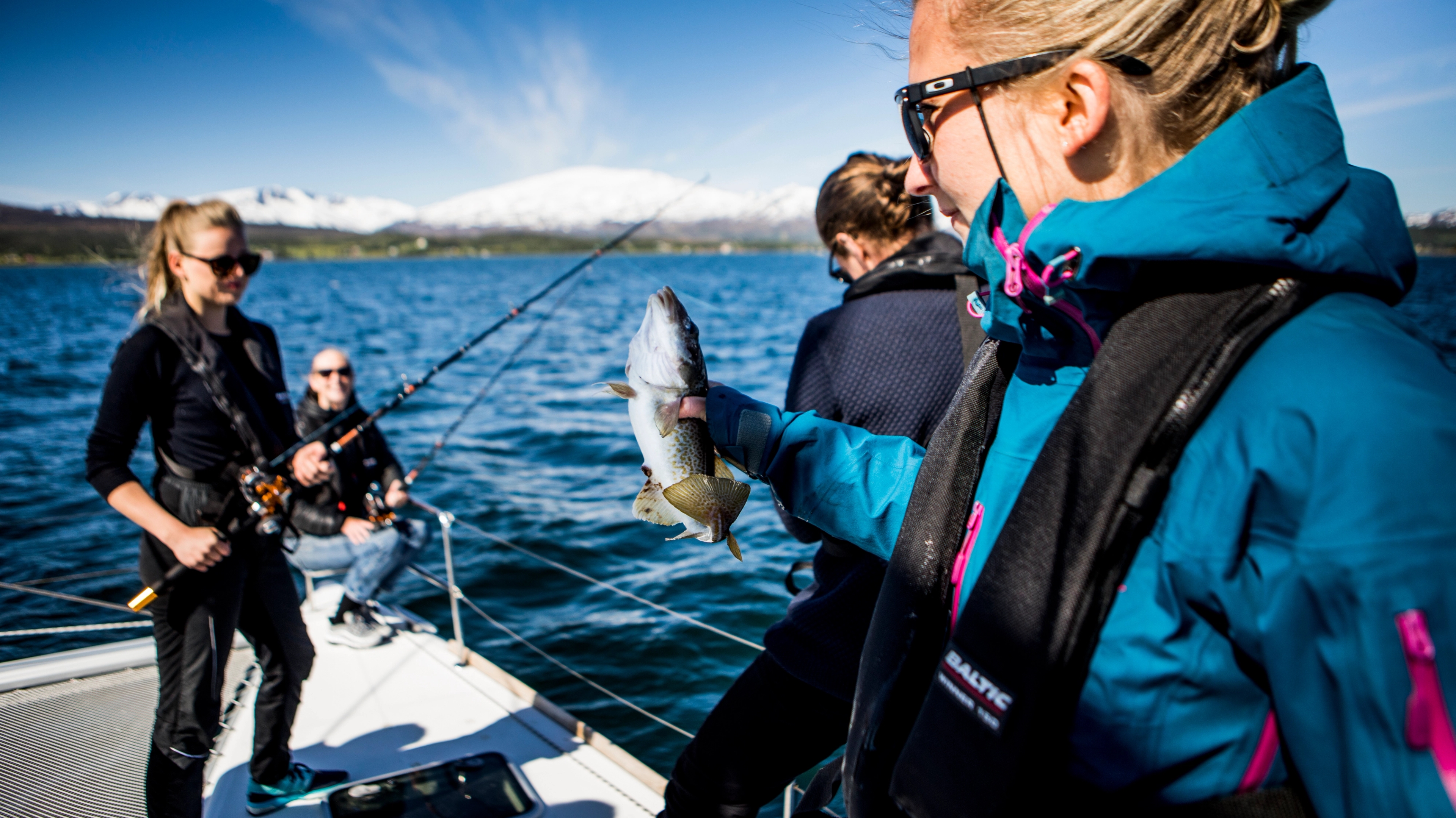 Many women fishing on a boat, one of them just caught a cod, Tromsø