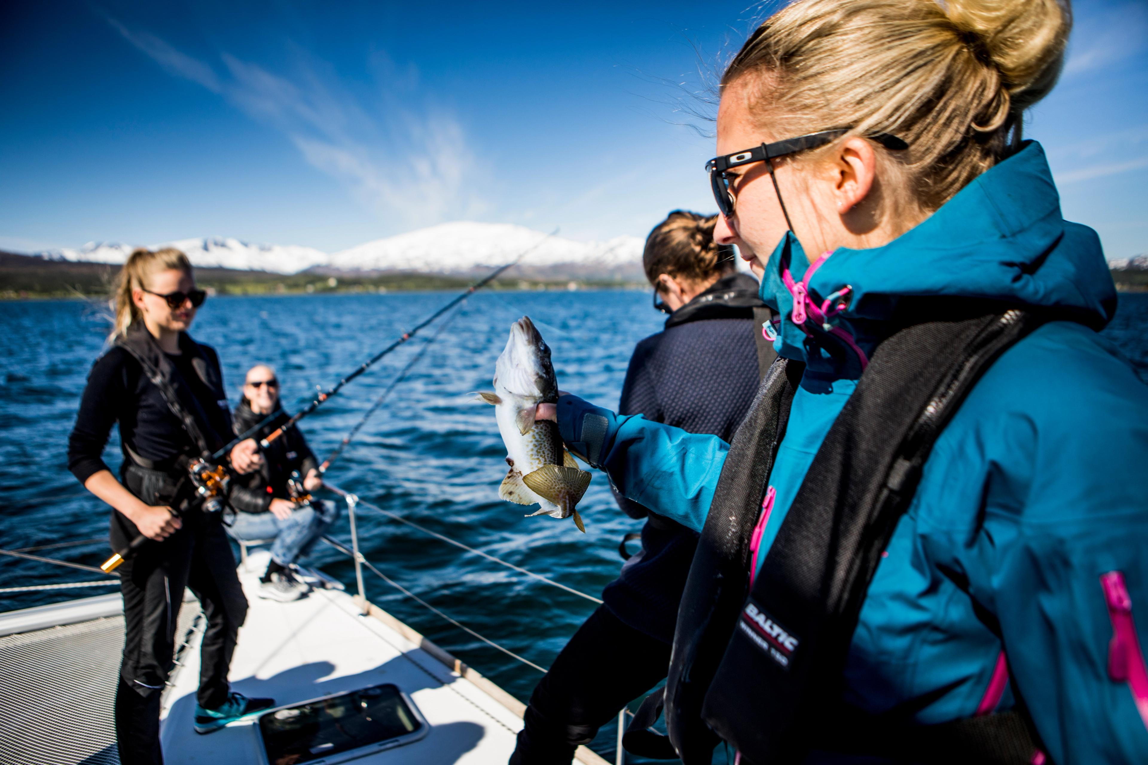 Many women fishing on a boat, one of them just caught a cod, Tromsø