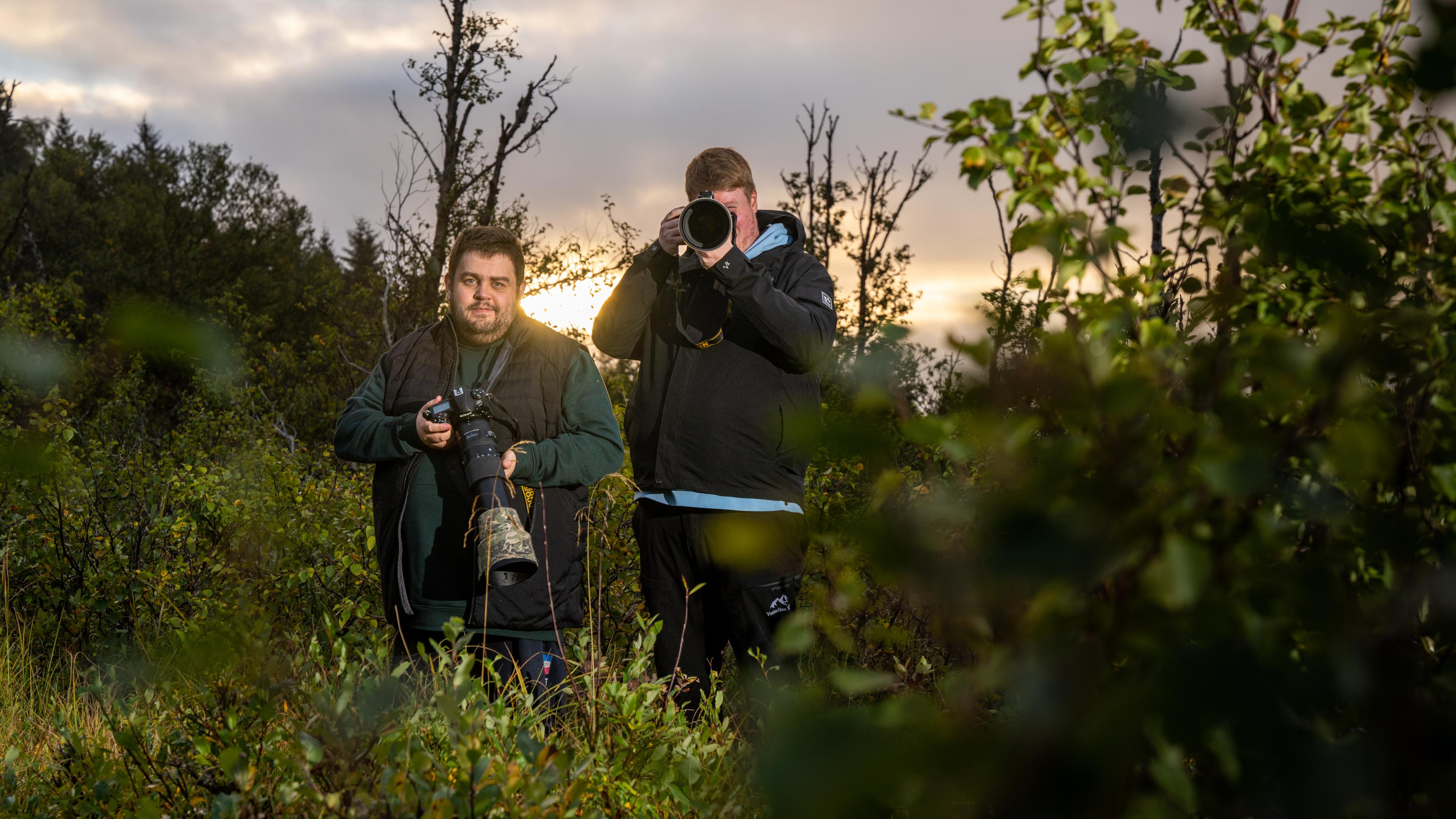 Wildlife photographers Marius and Jens Birkeland are posing with their cameras in the bushes