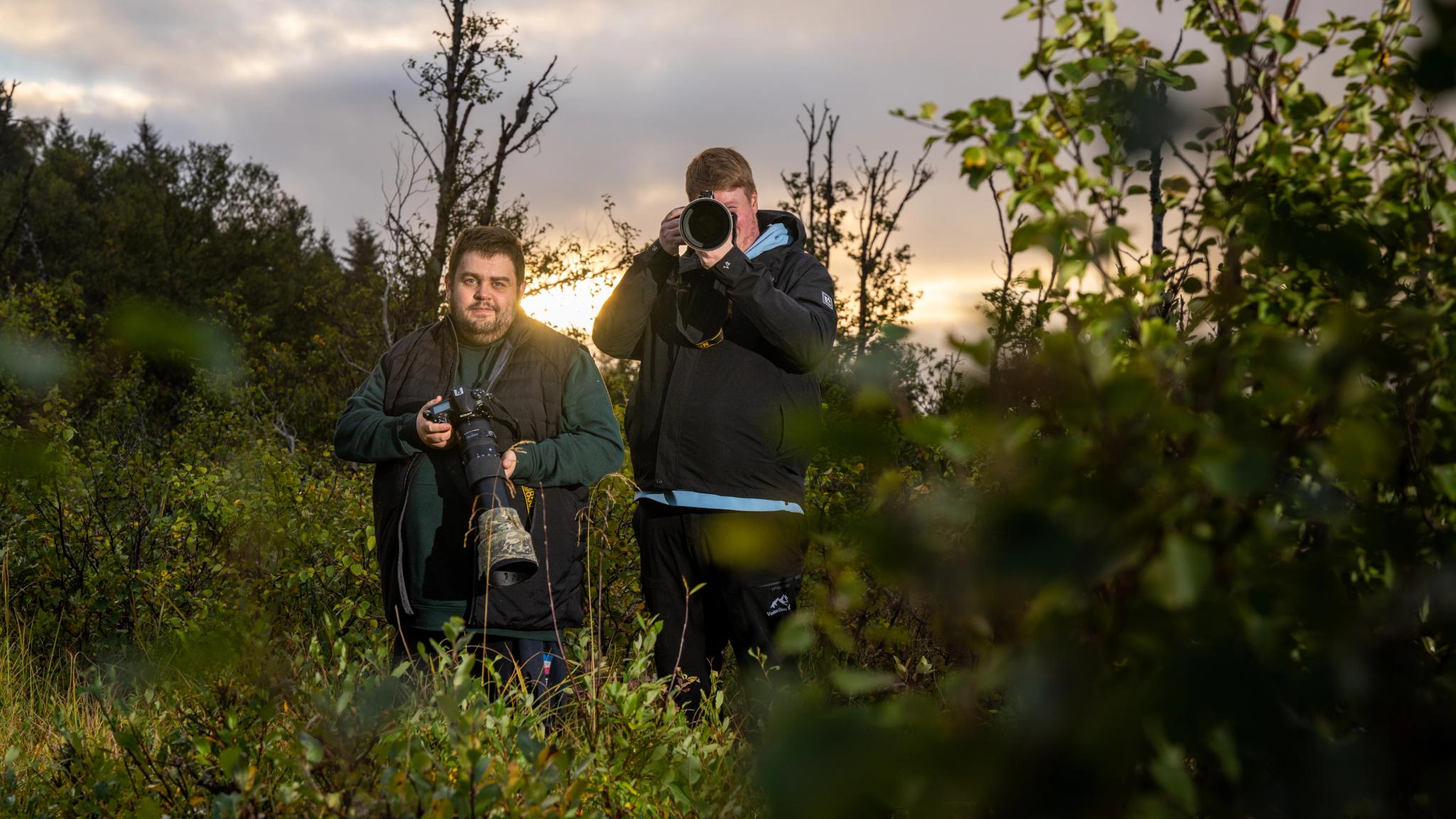 Wildlife photographers Marius and Jens Birkeland are posing with their cameras in the bushes