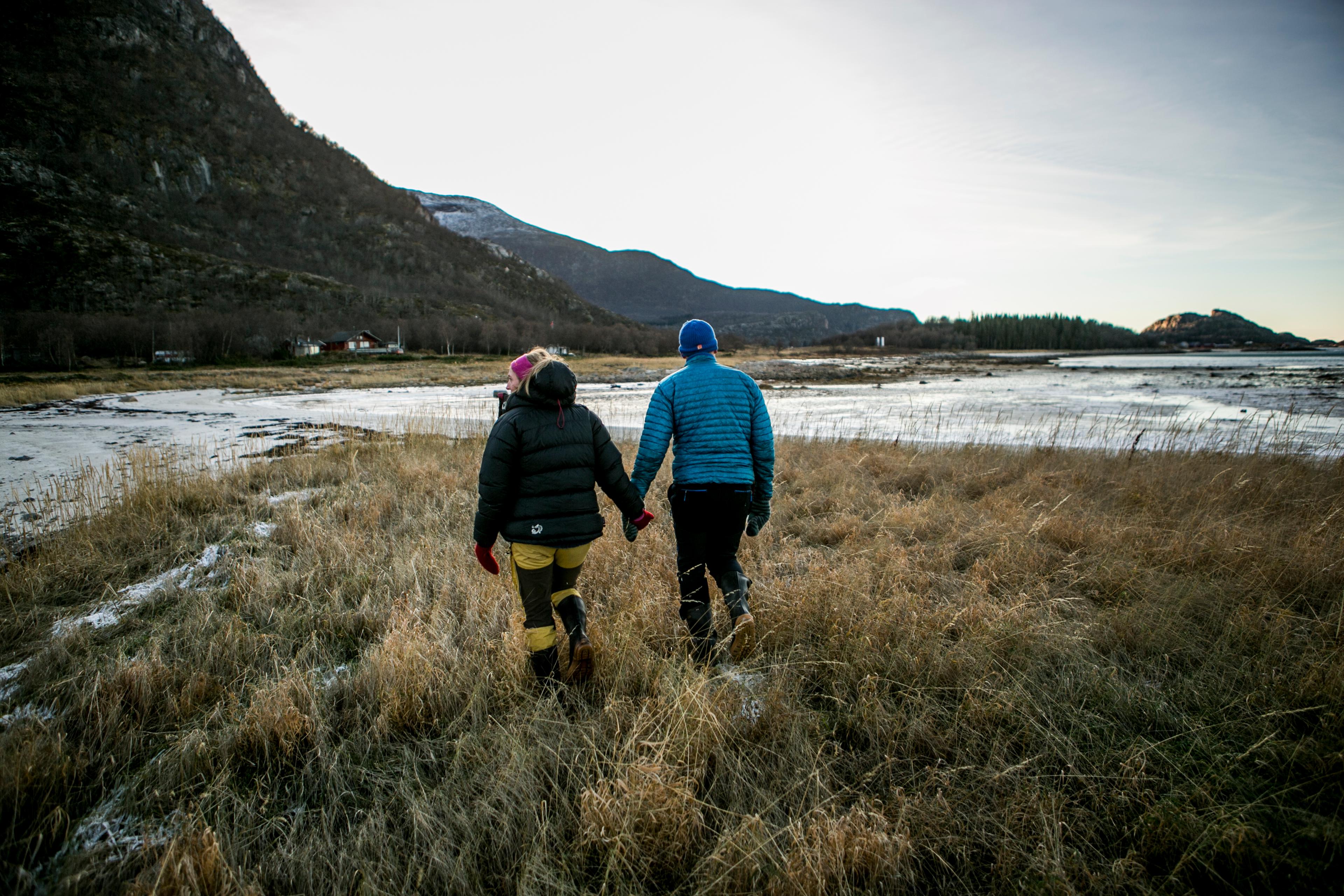 To personer holder hender mens de vandrer i fjæra i Steigen i Nord-Norge