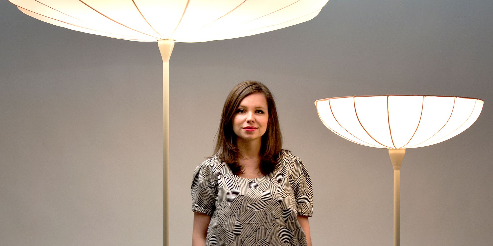 Designer Kristine Five Melvær standing in front of her own designer lamps called Spring