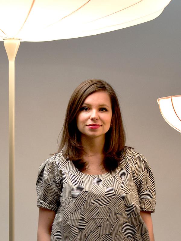 Designer Kristine Five Melvær standing in front of her own designer lamps called Spring