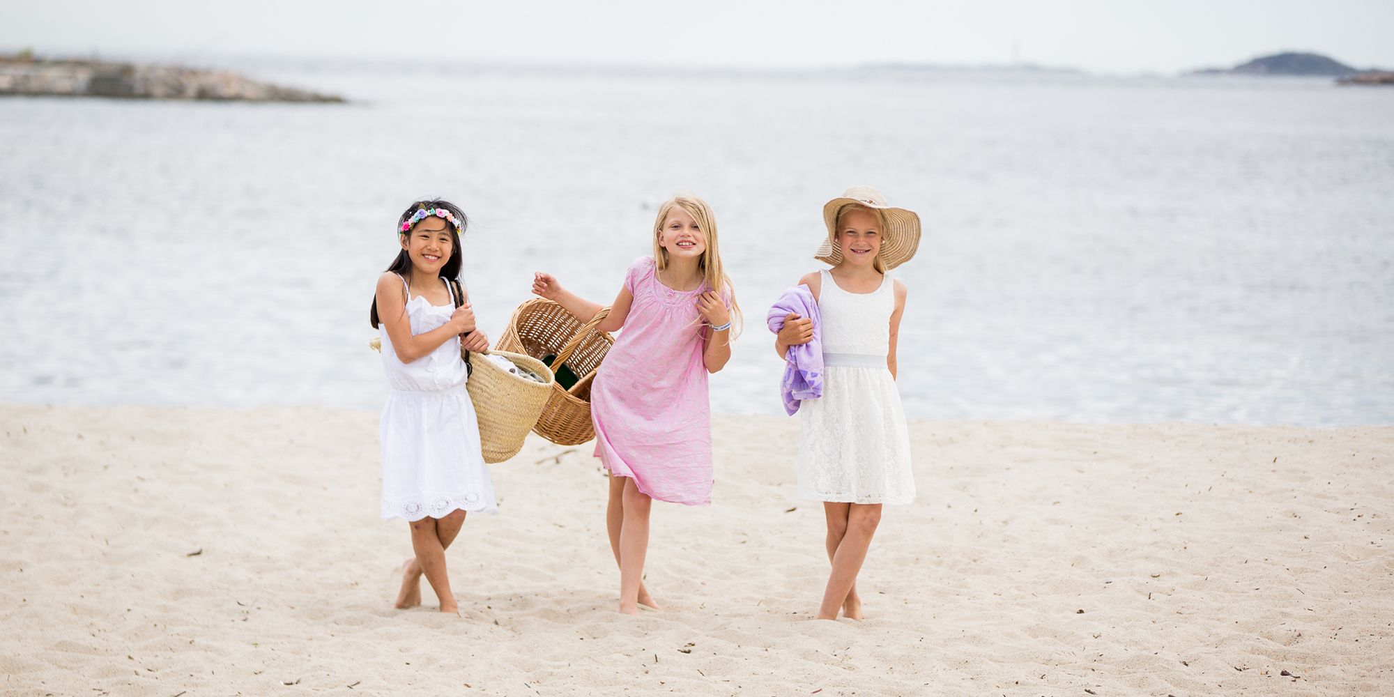Three girls in dresses at Bystranda beach in Kristiansand, Southern Norway