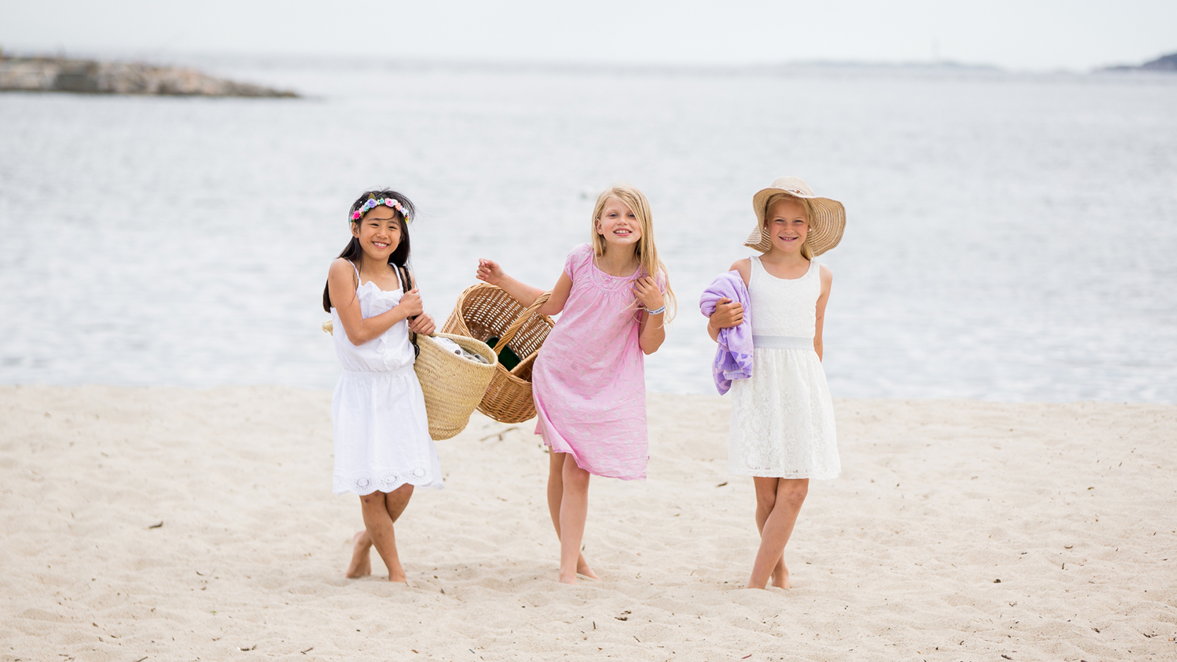 Three girls in dresses at Bystranda beach in Kristiansand, Southern Norway