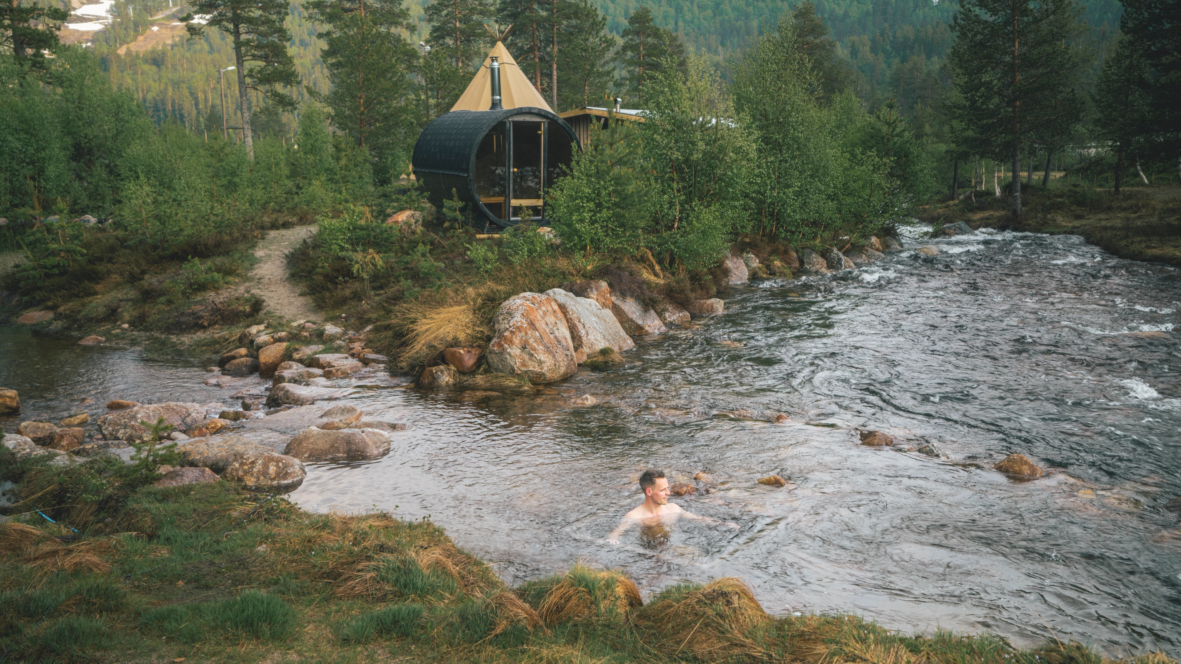 A man taking a cold plunge in the river at Brokkestøylen glamping
