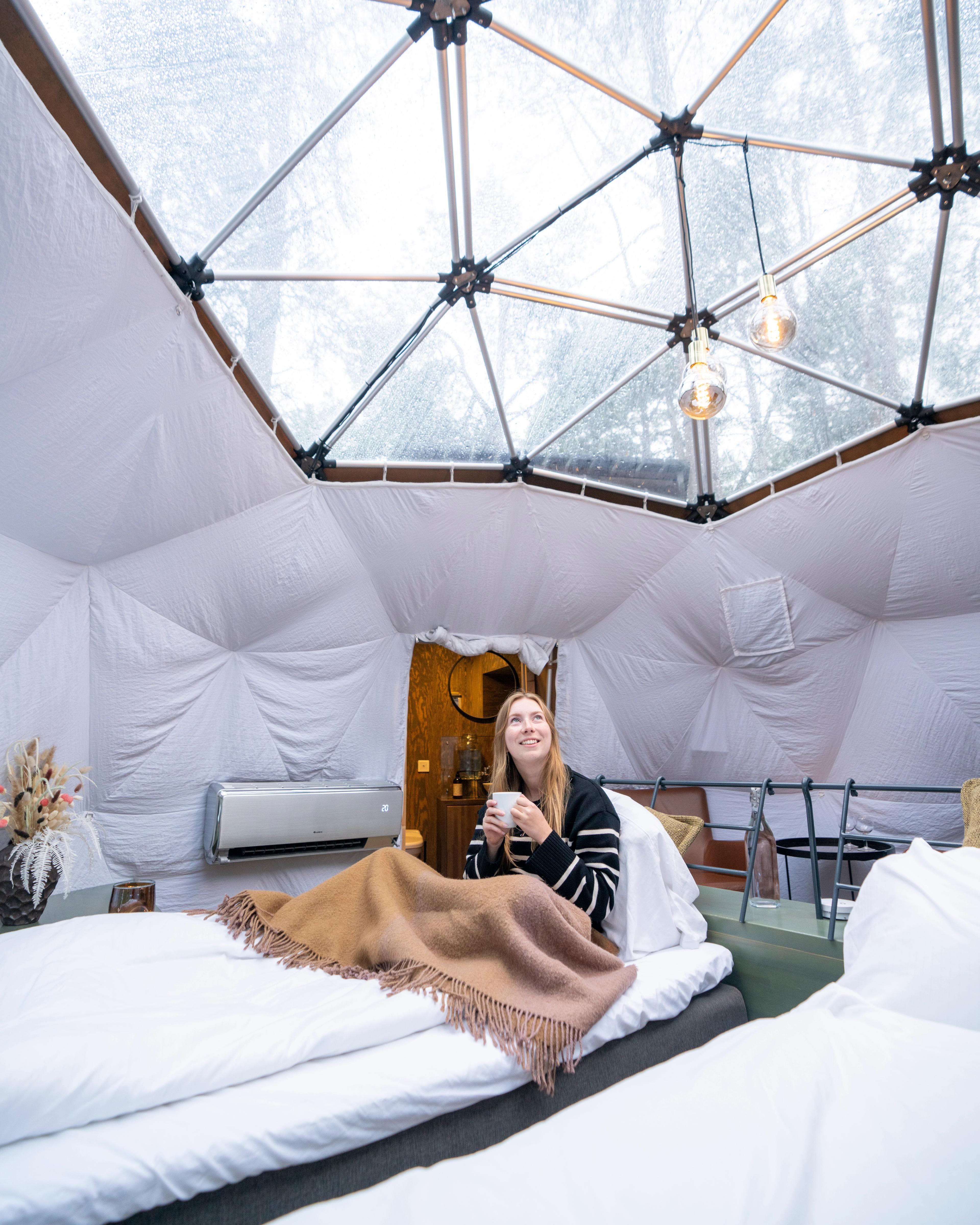 A woman enjoying the view from a Glød Aurora Canvas Dome in Alta