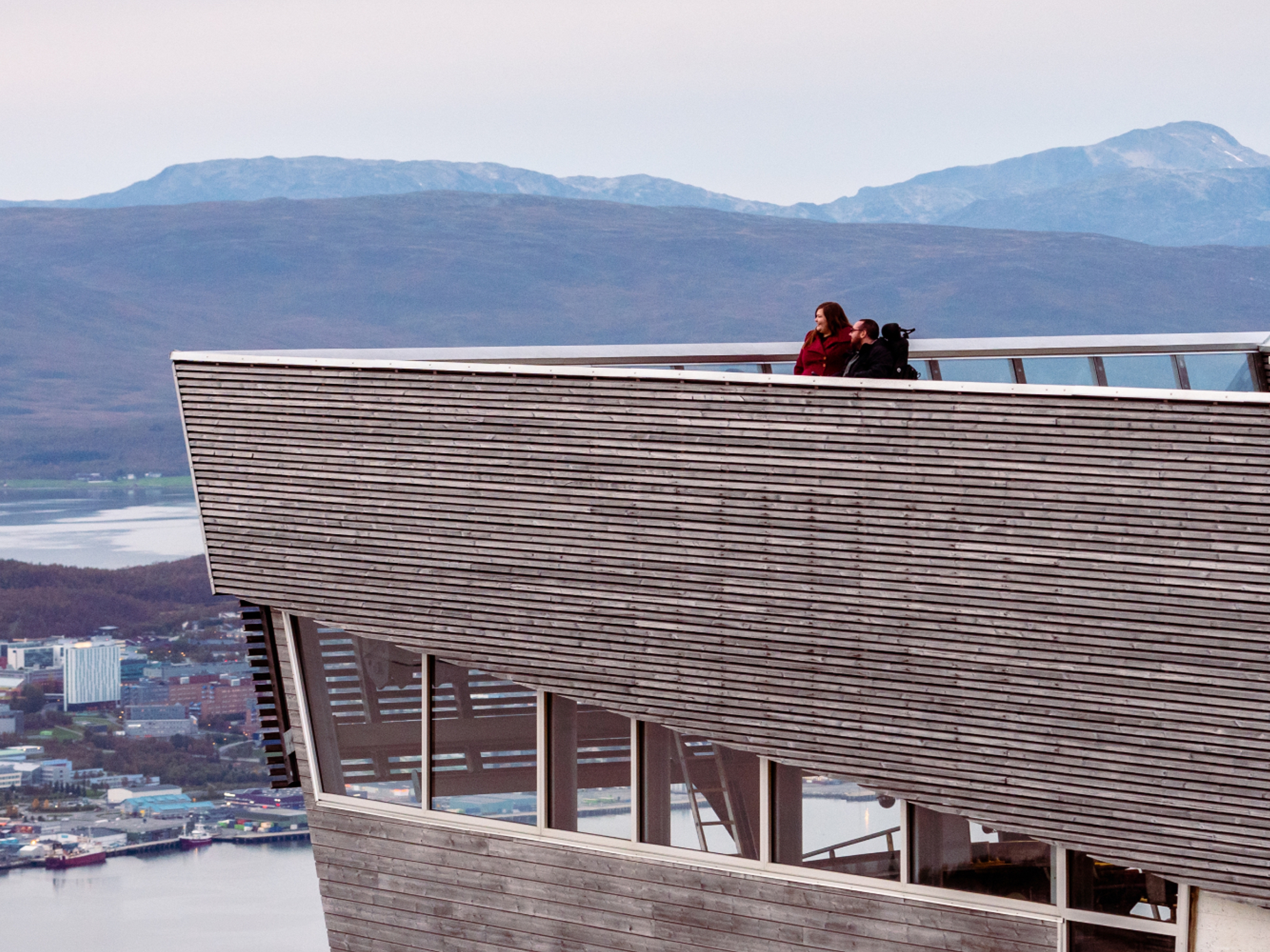 A couple overlooking Tromsø from a viewing point at a tall building