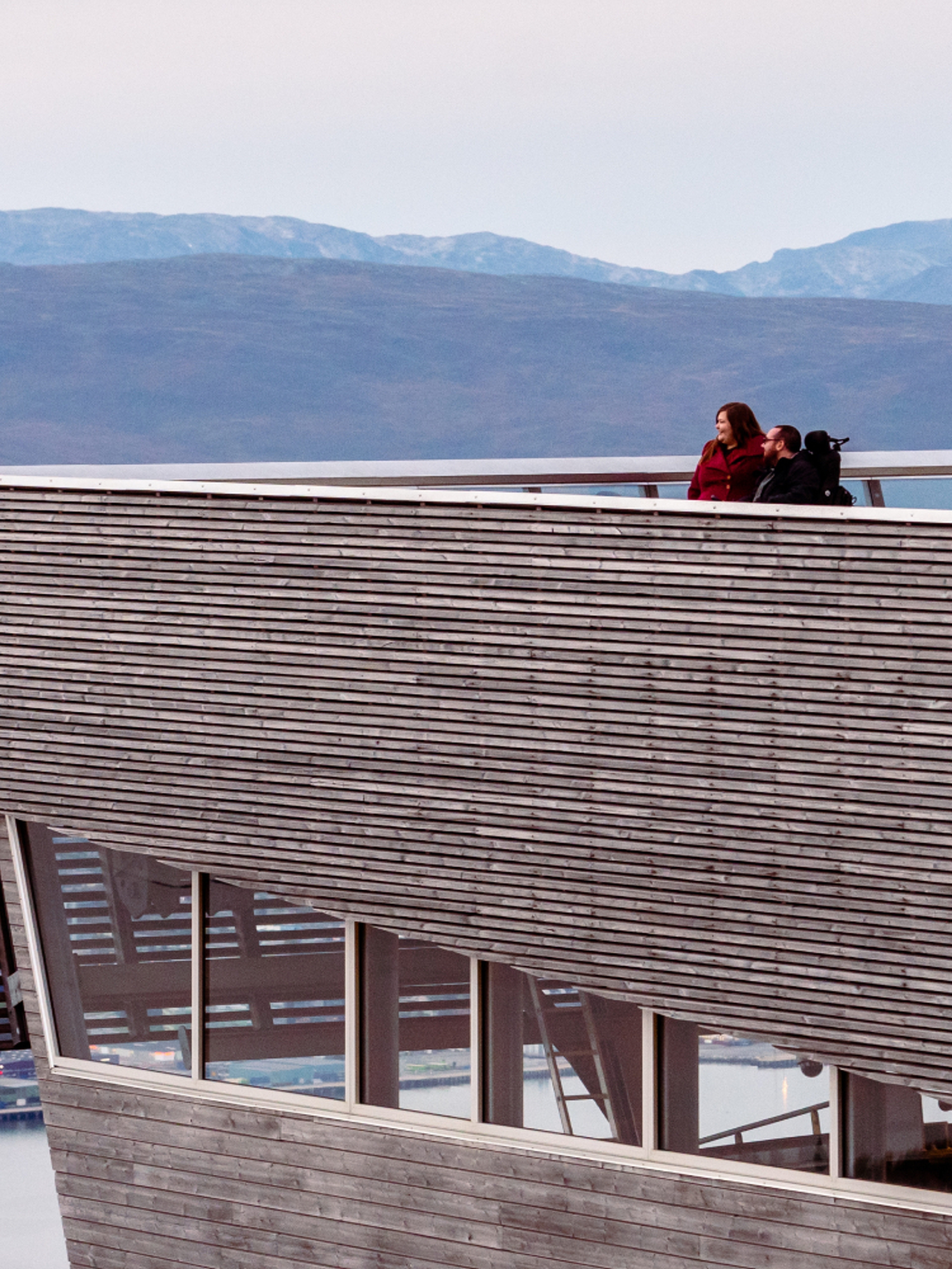 A couple overlooking Tromsø from a viewing point at a tall building