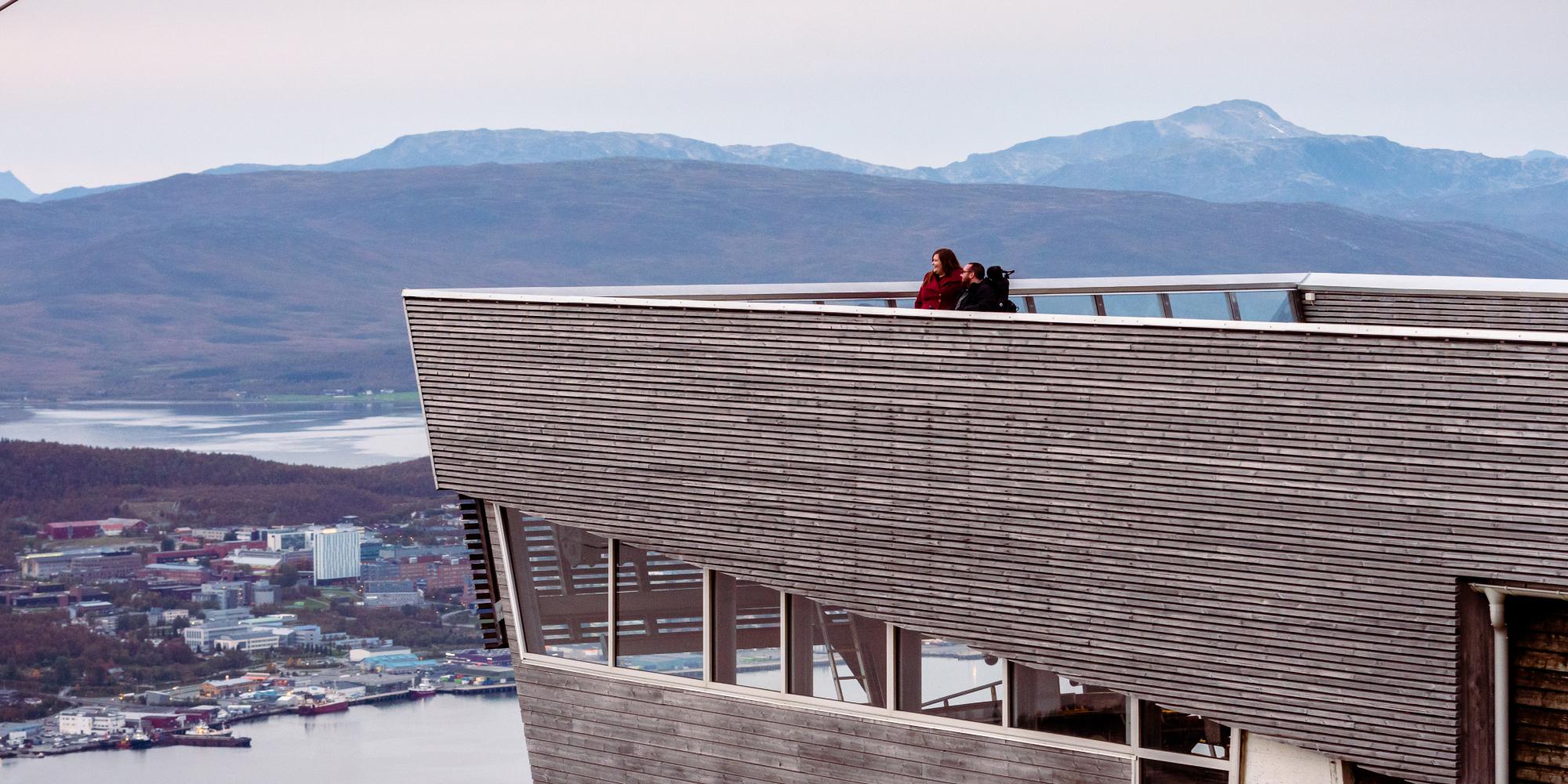 A couple overlooking Tromsø from a viewing point at a tall building