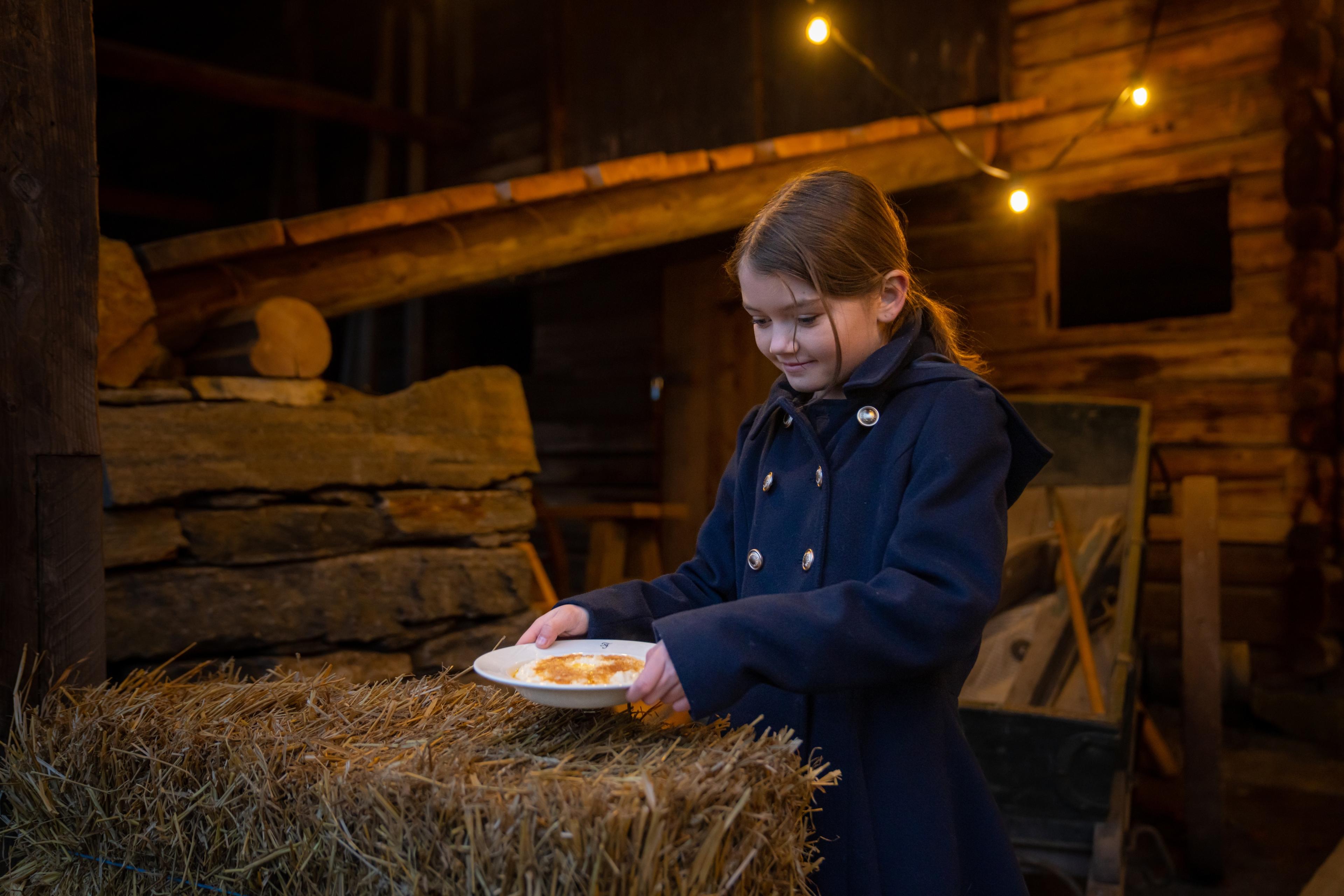 En jente setter ut en skål med nissegrøt til julenissen