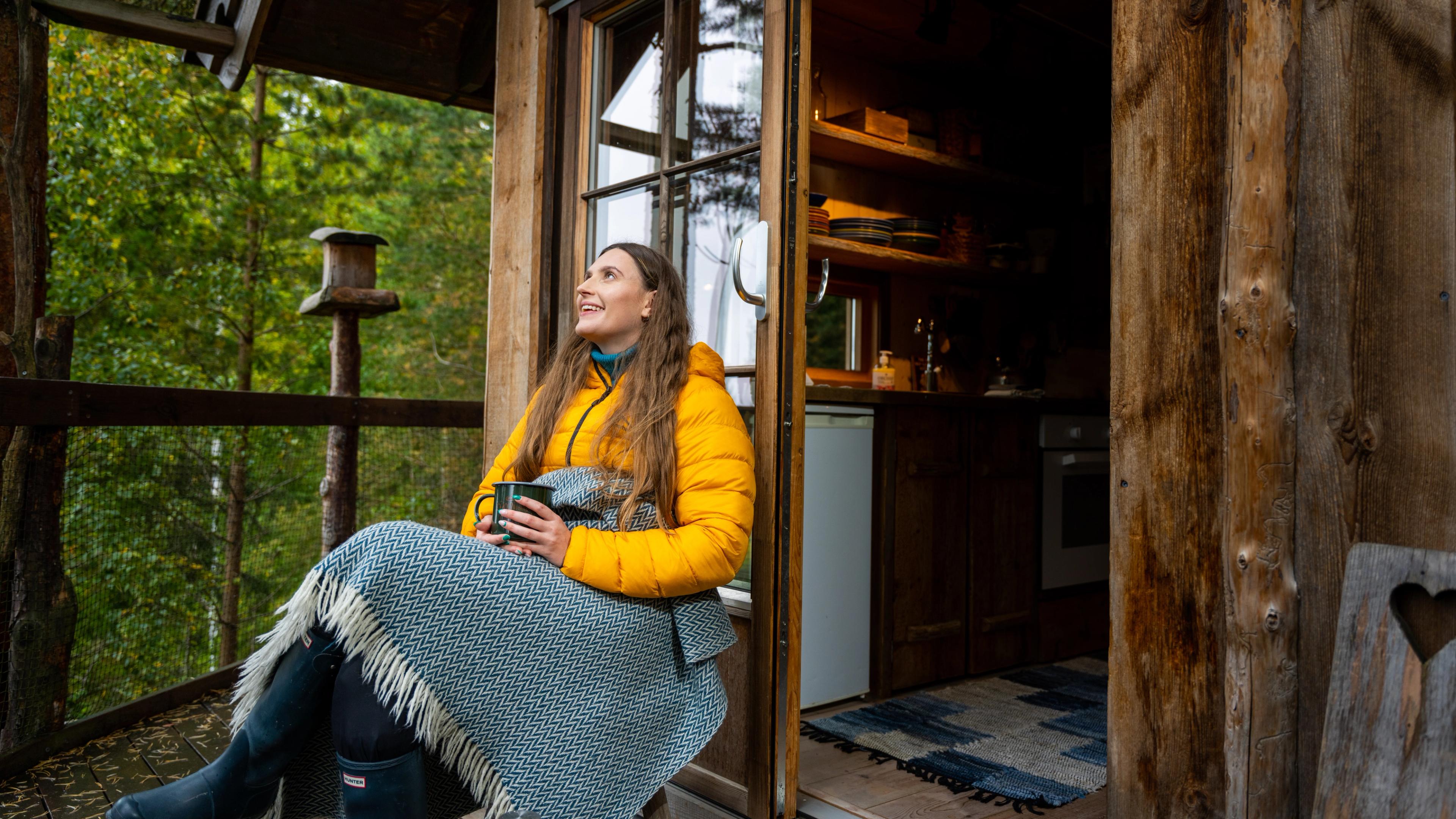 A woman outside a log cabin