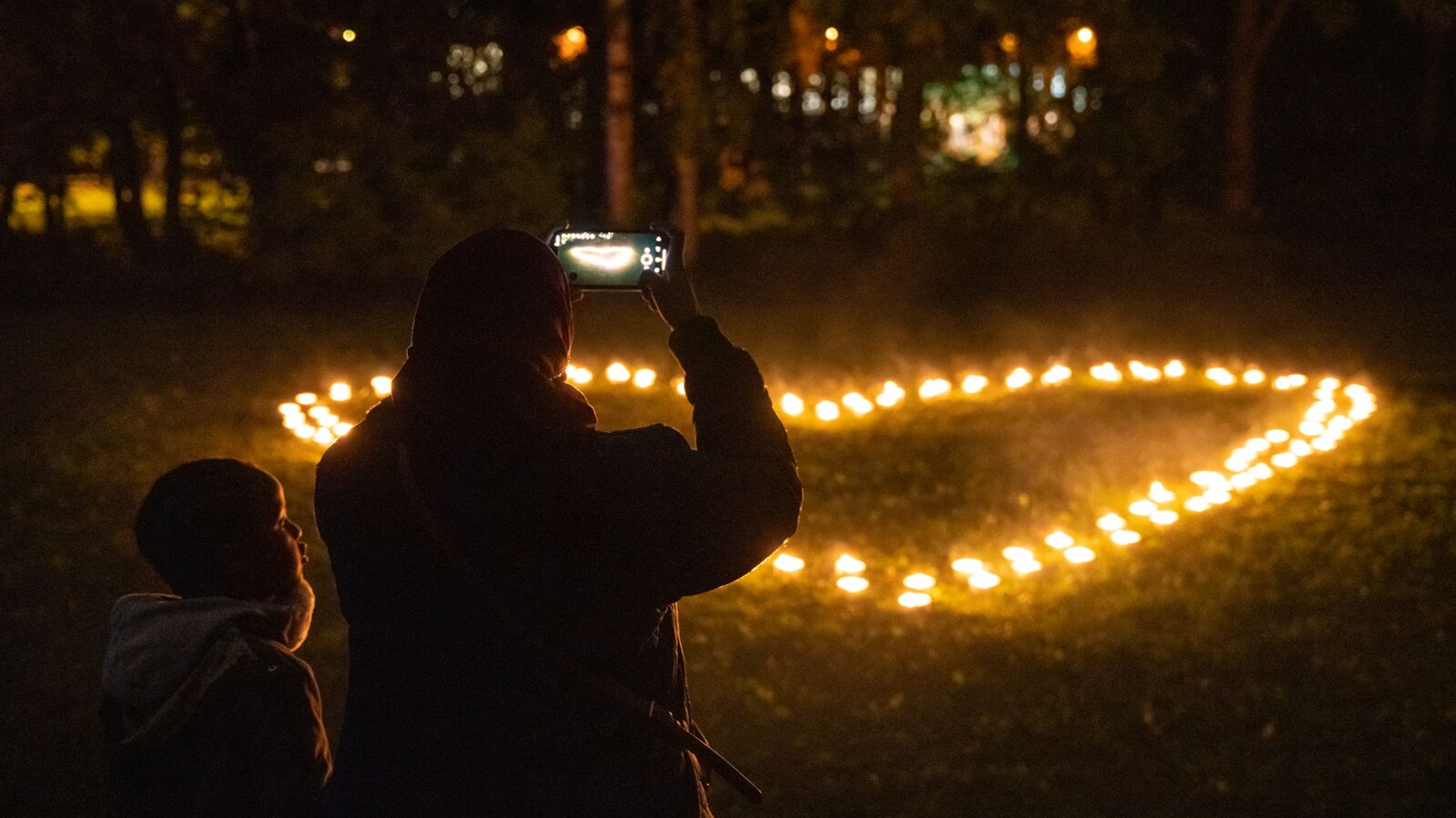 To people taking a photo of heart shaped lights at Elvelangs light festival in Oslo