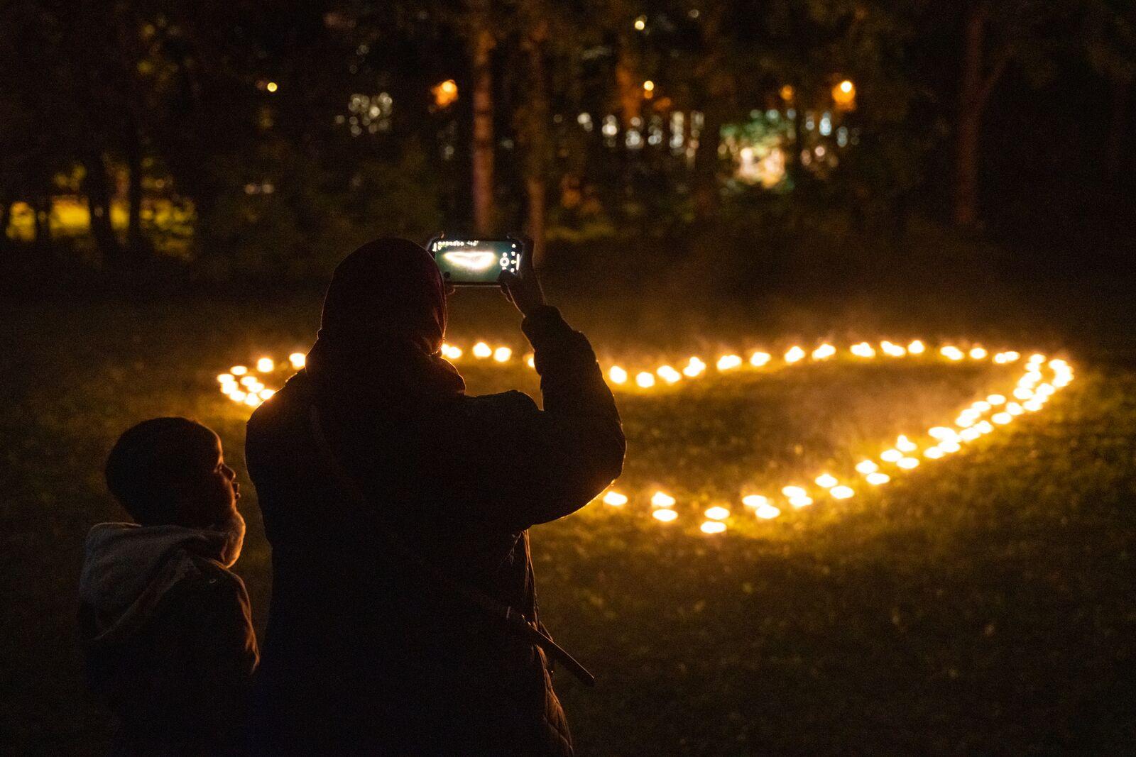 To people taking a photo of heart shaped lights at Elvelangs light festival in Oslo