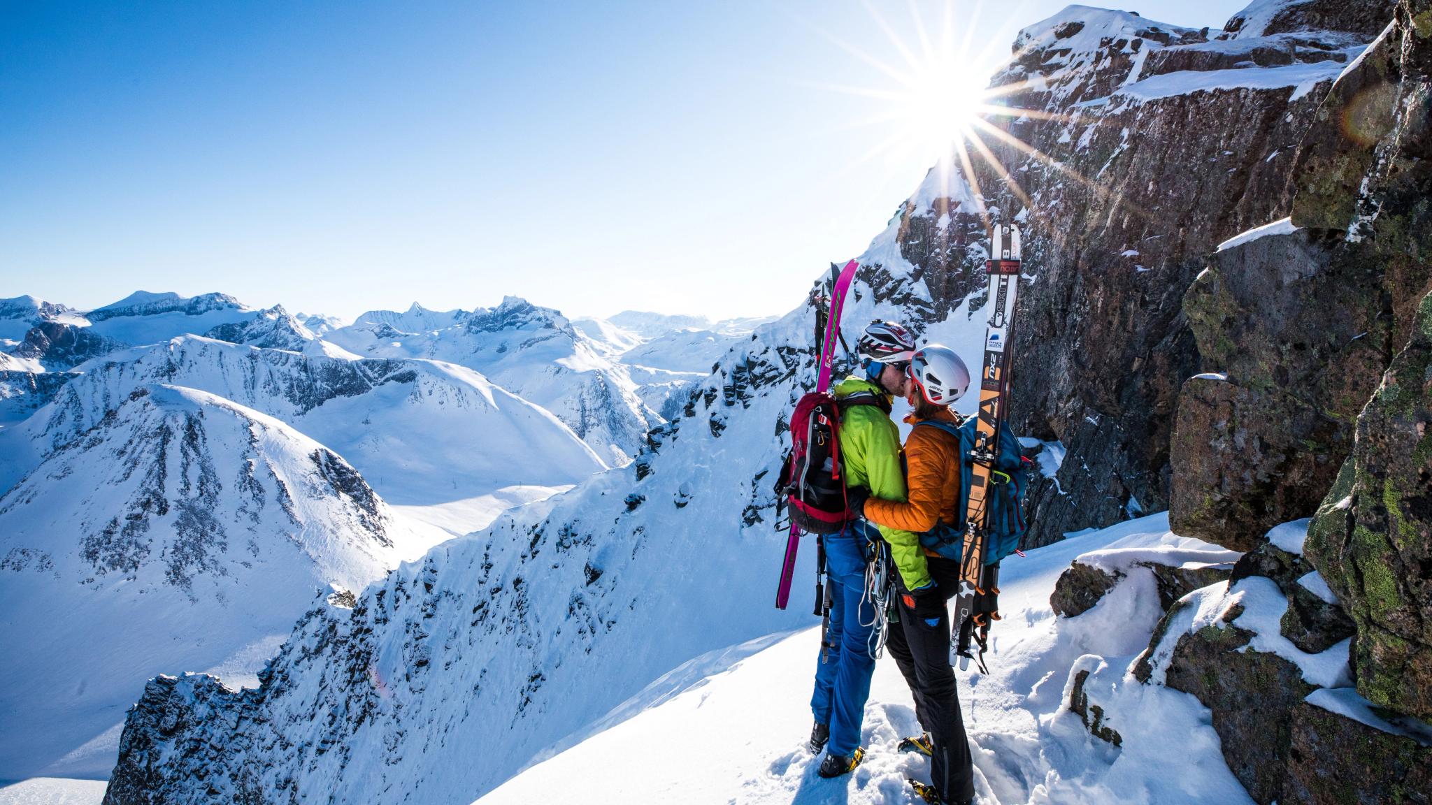 Couple kissing with skis on their back in the mountain of Romsdalen, Fjord Norway