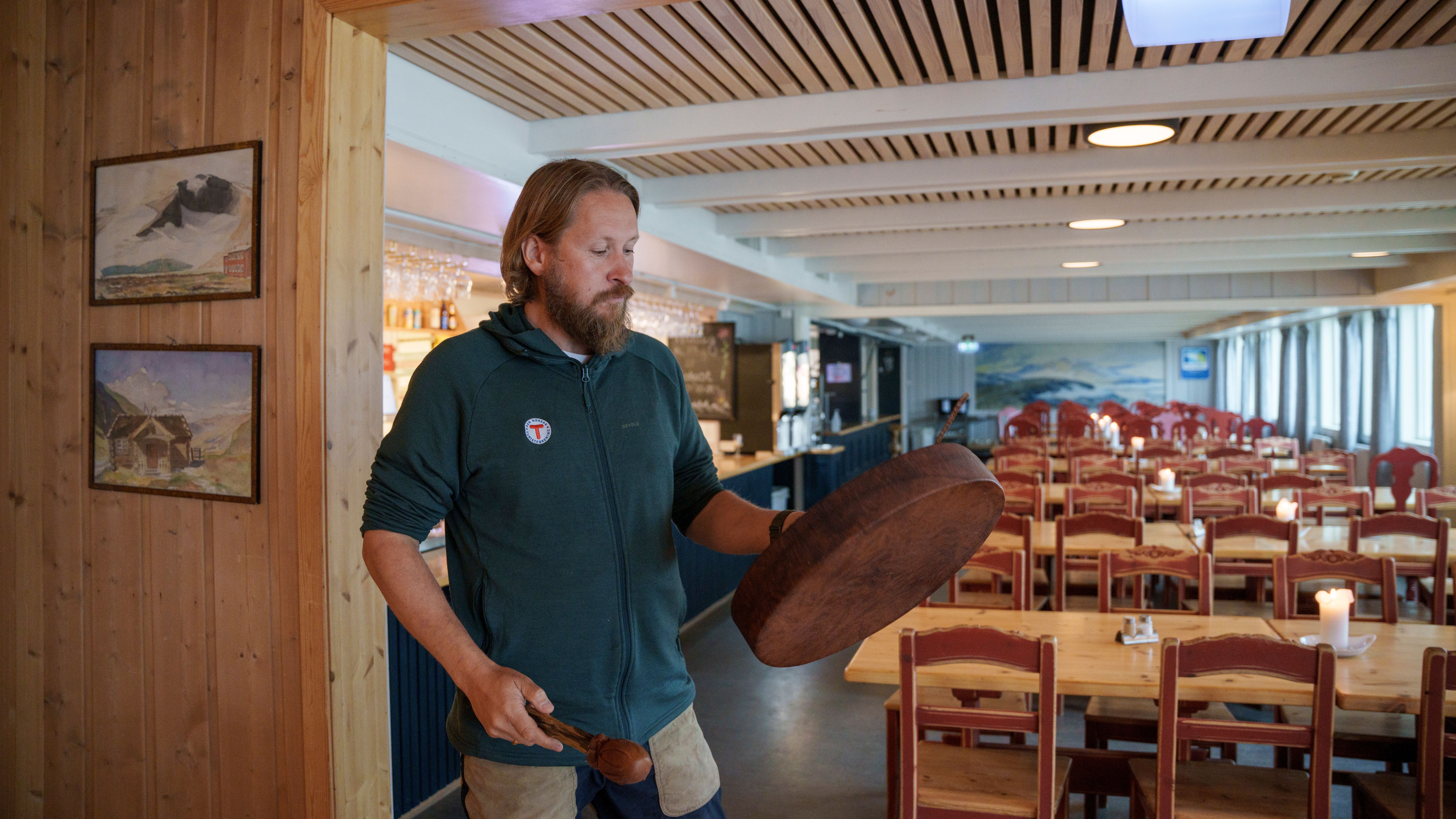 A man holding a drum inside a mountain lodge