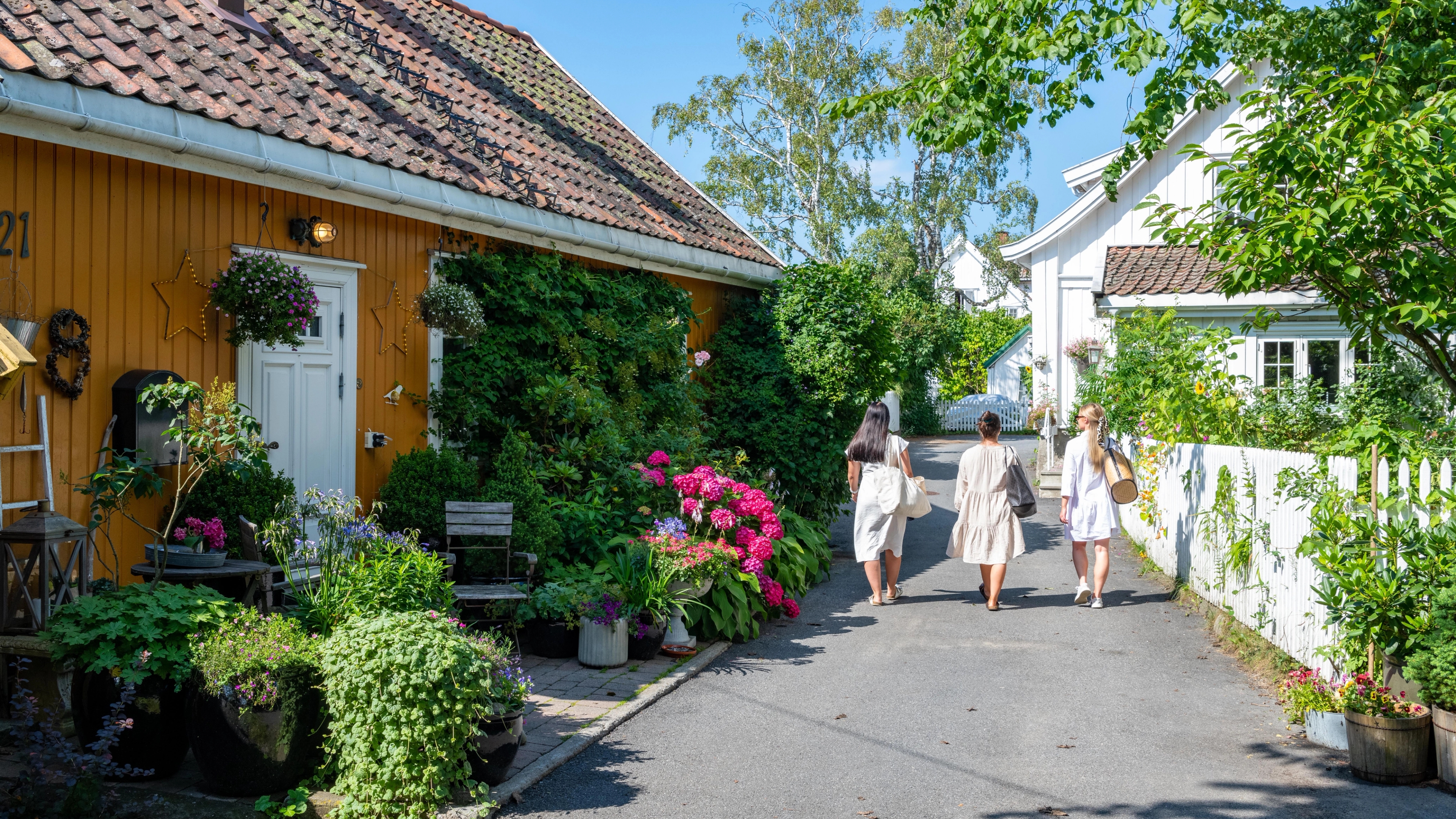 Three women walking past wooden houses in Drøbak
