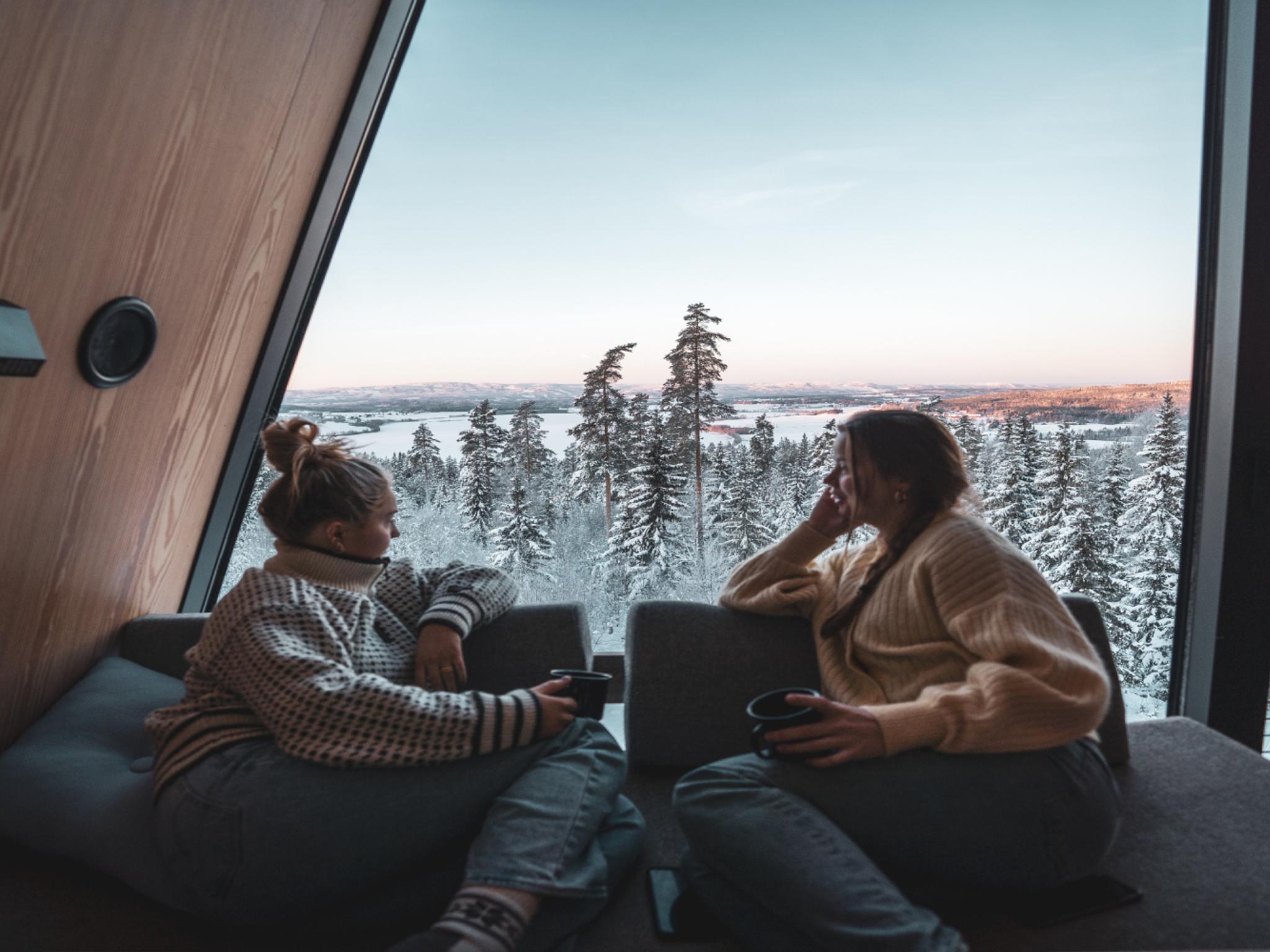 Two people looking out of a window in a tree top cabin in Finnskogen forest in Solør, Norway.