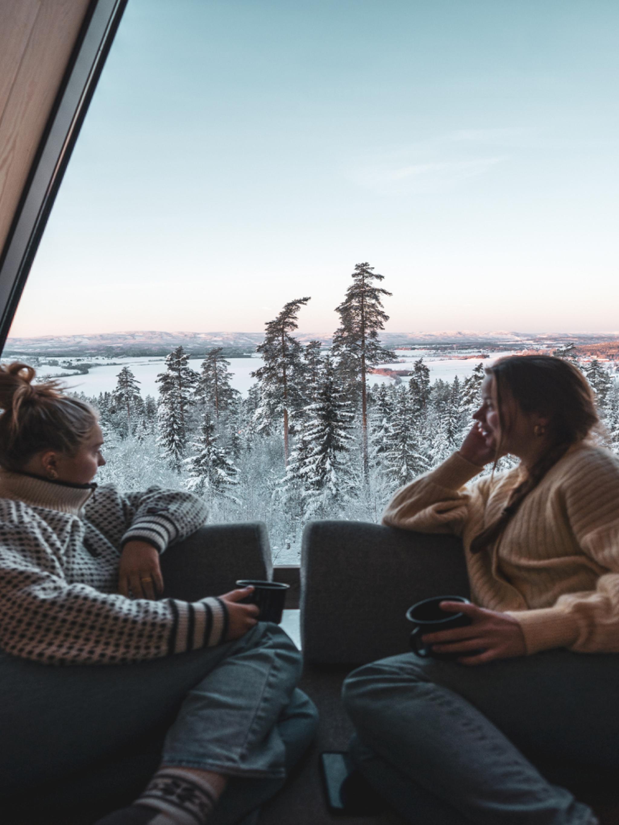 Two people looking out of a window in a tree top cabin in Finnskogen forest in Solør, Norway.
