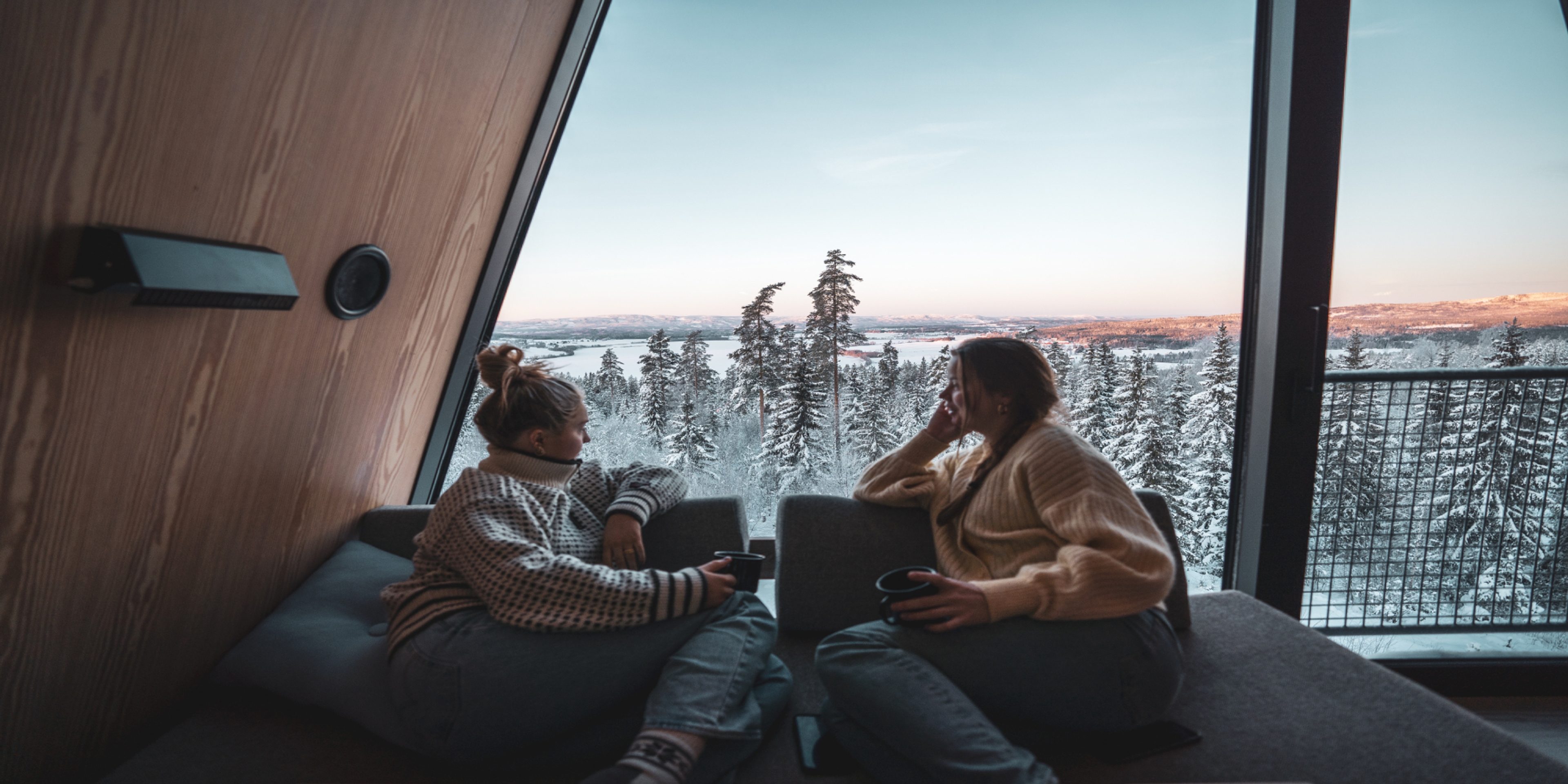 Two people looking out of a window in a tree top cabin in Finnskogen forest in Solør, Norway.