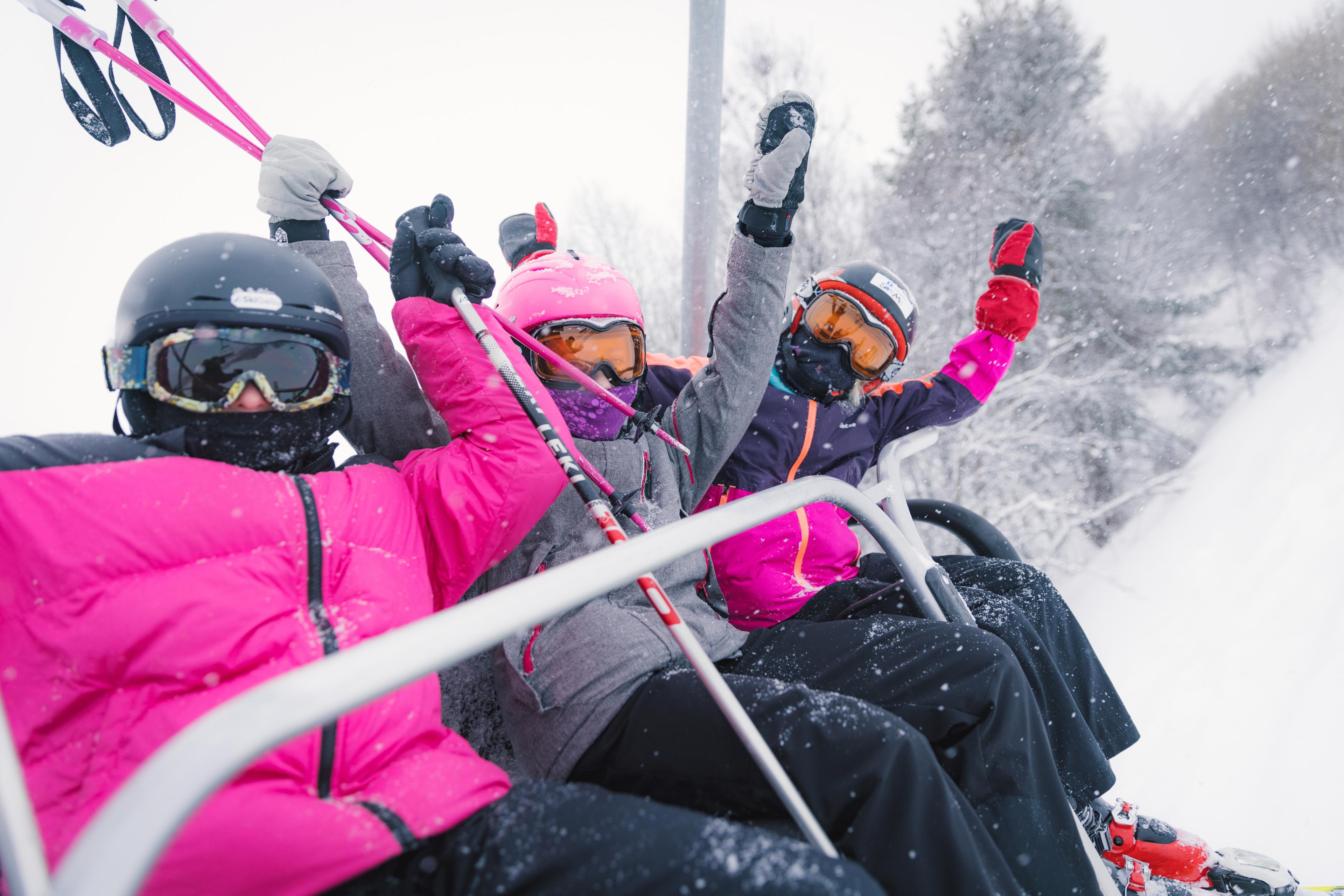 Three happy girls sitting in a ski lift in Geilo ski resort, Eastern Norway