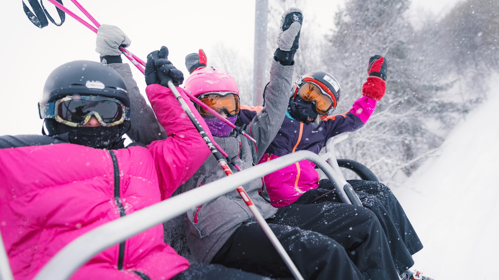 Three happy girls sitting in a ski lift in Geilo ski resort, Eastern Norway