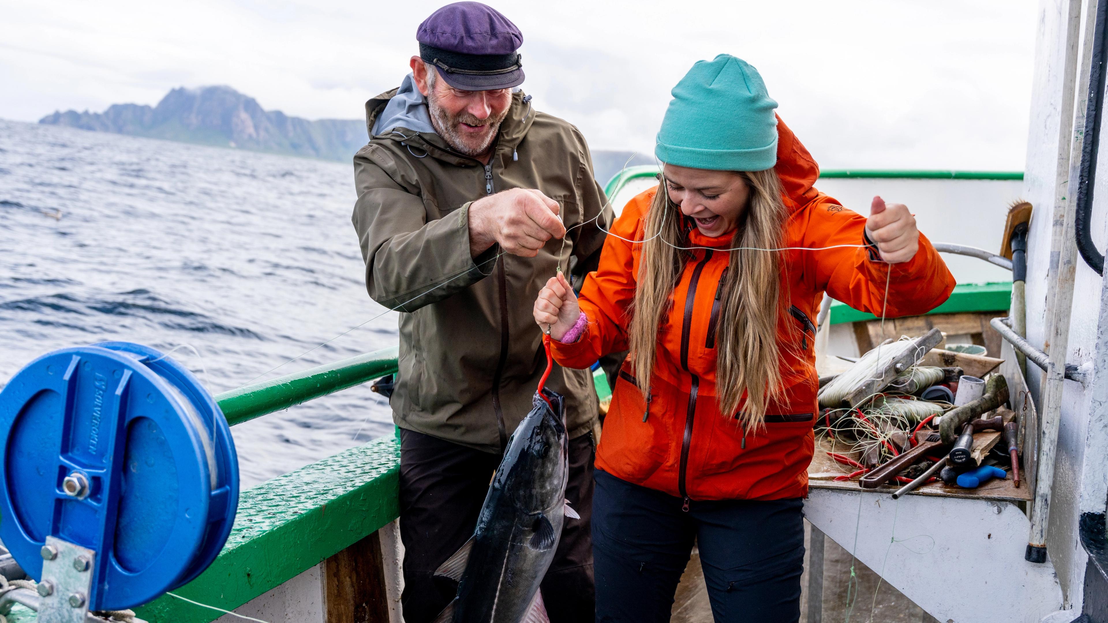 A man and a woman just caught a fish at sea