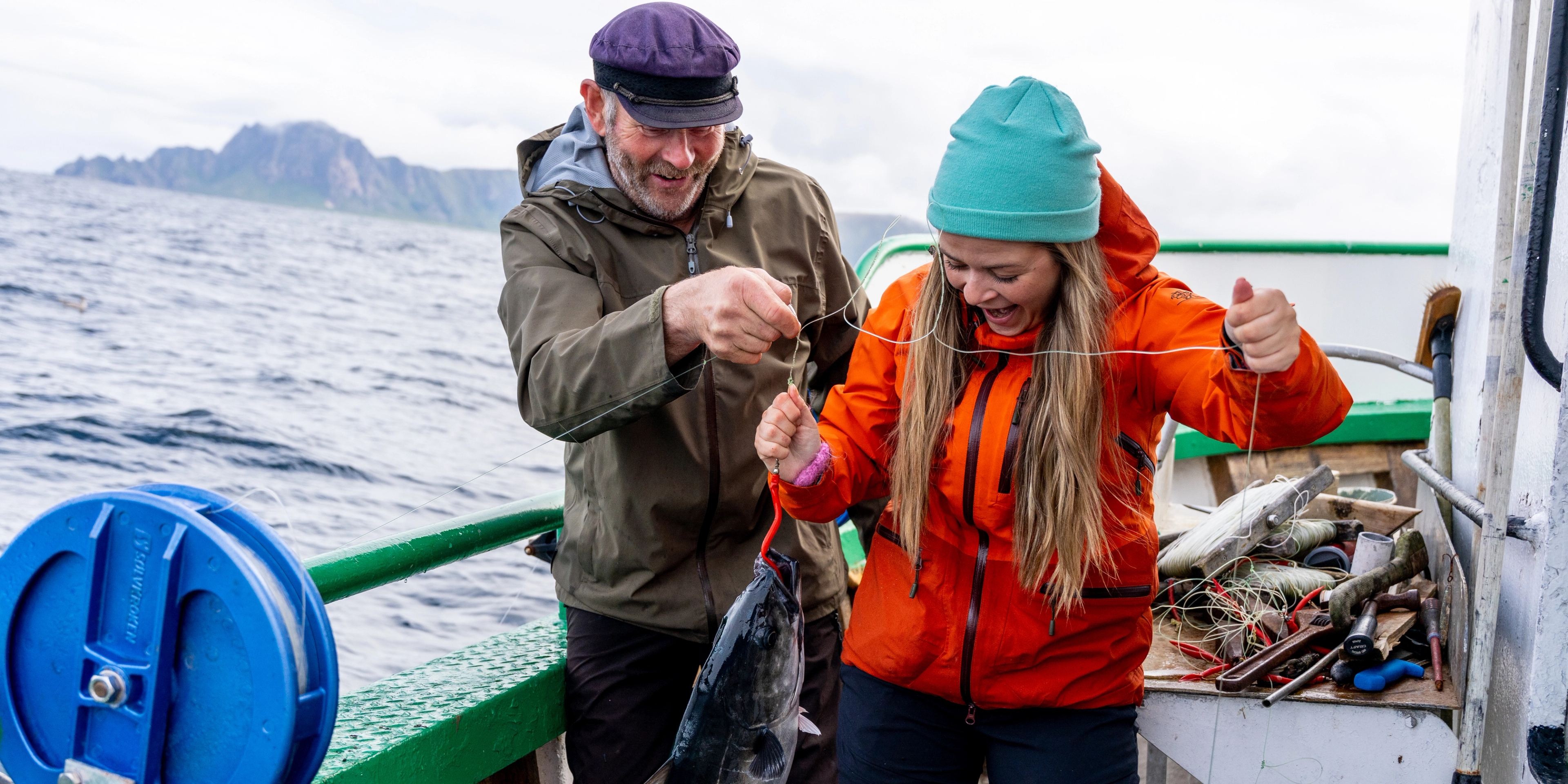 A man and a woman just caught a fish at sea