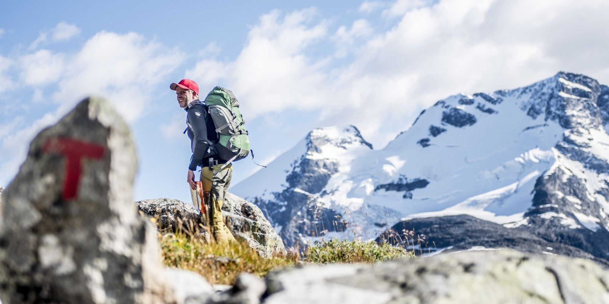 A man hiking past a safety cairn in the mountains