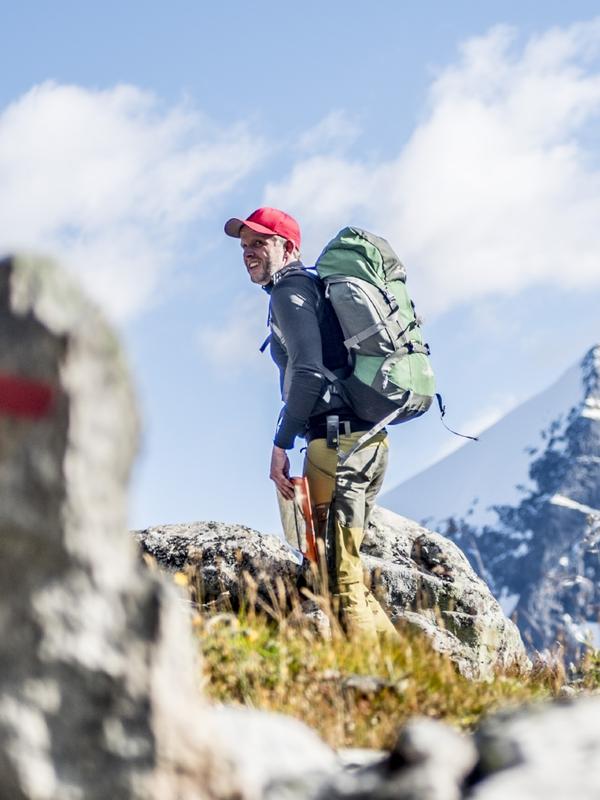 A man hiking past a safety cairn in the mountains