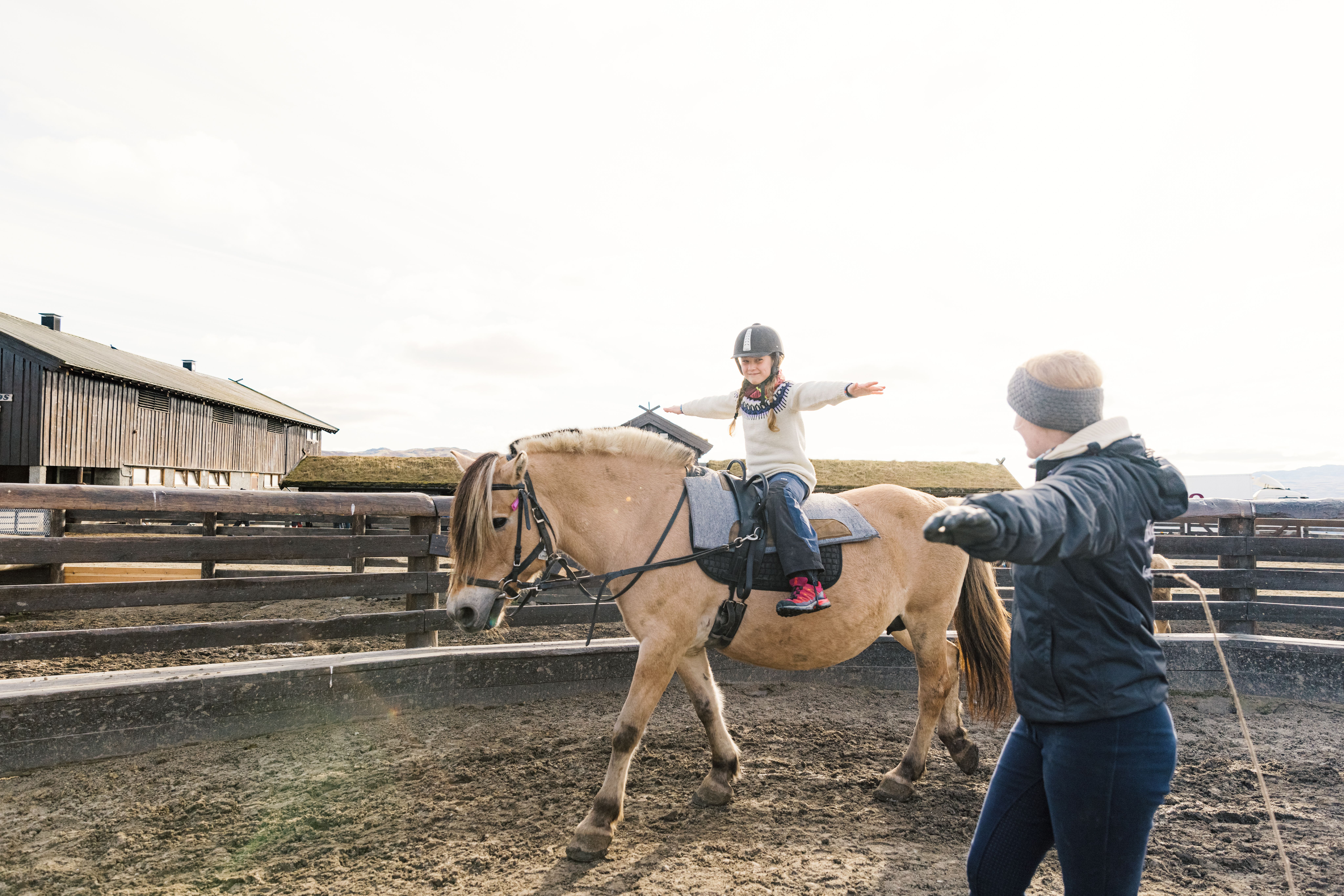 A young girl riding a horse with an instructor