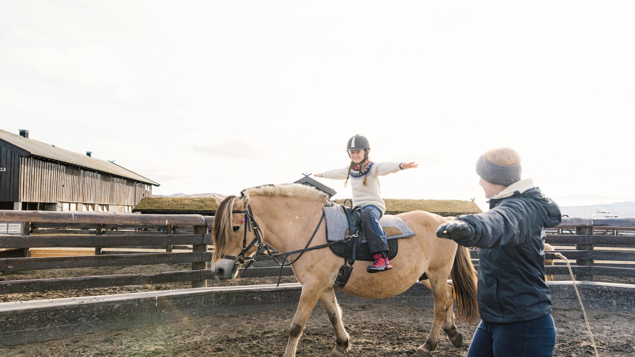A young girl riding a horse with an instructor