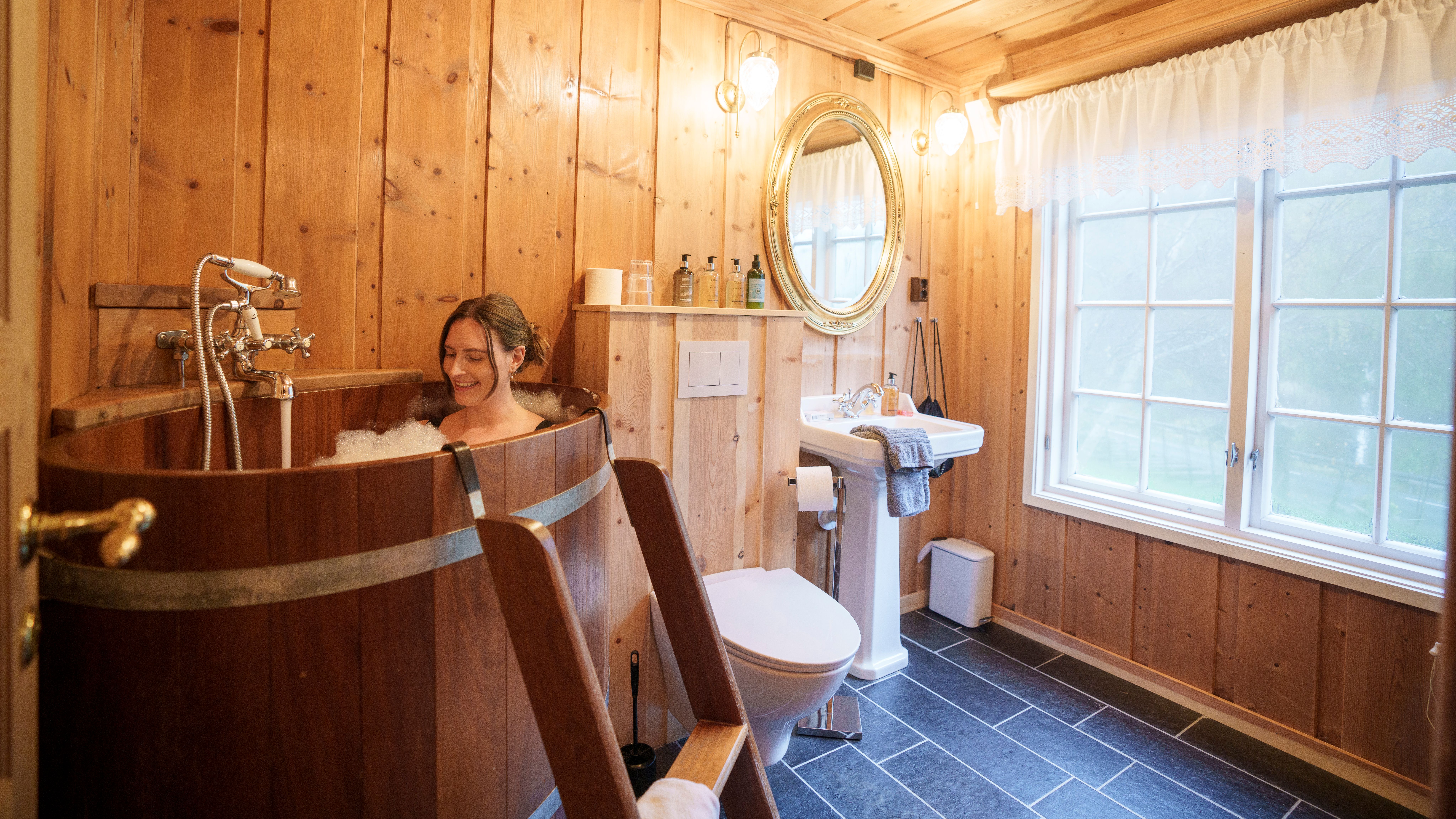 A woman in a hot tub inside a hotel room at Røisheim hotell