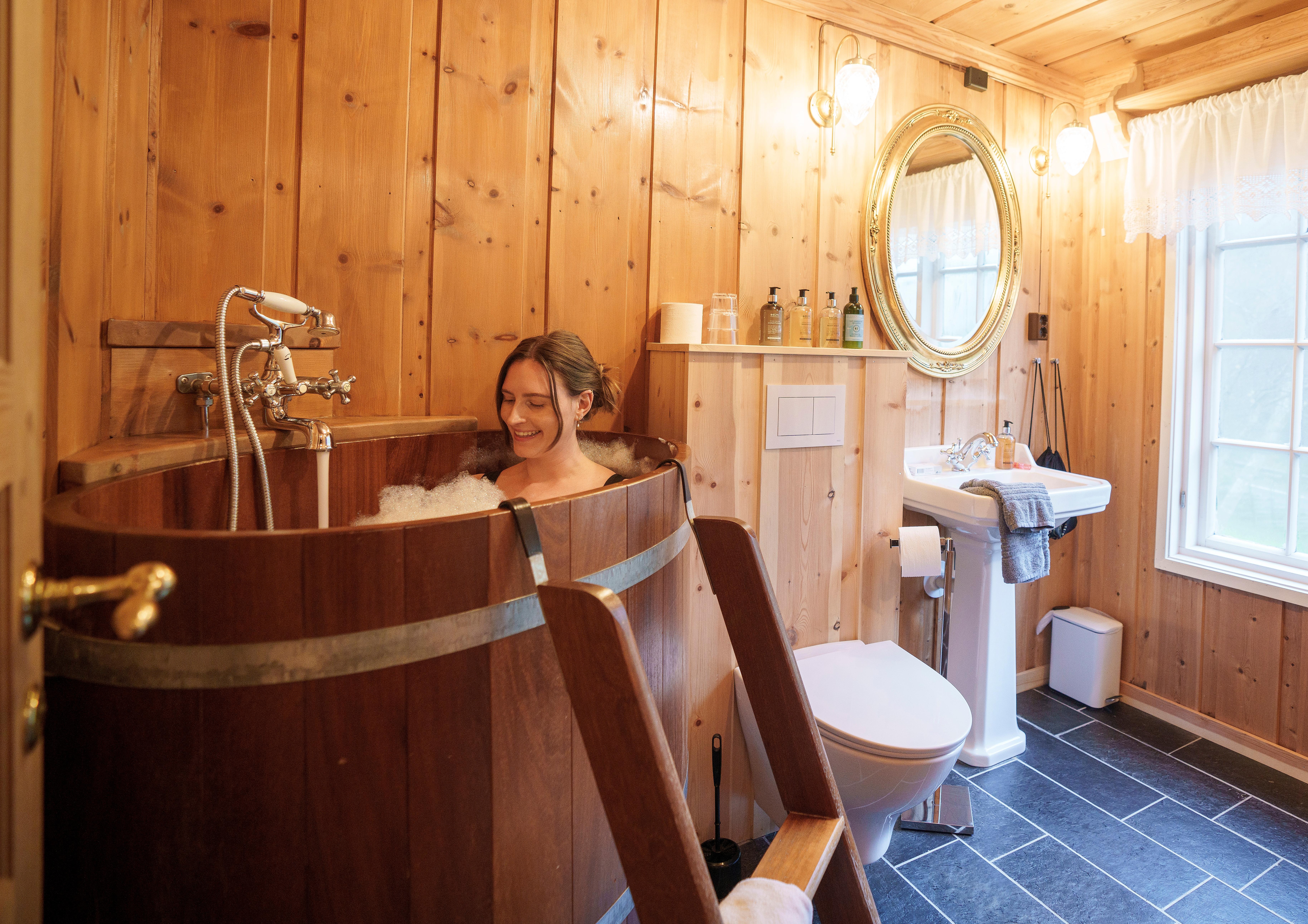 A woman in a hot tub inside a hotel room at Røisheim hotell