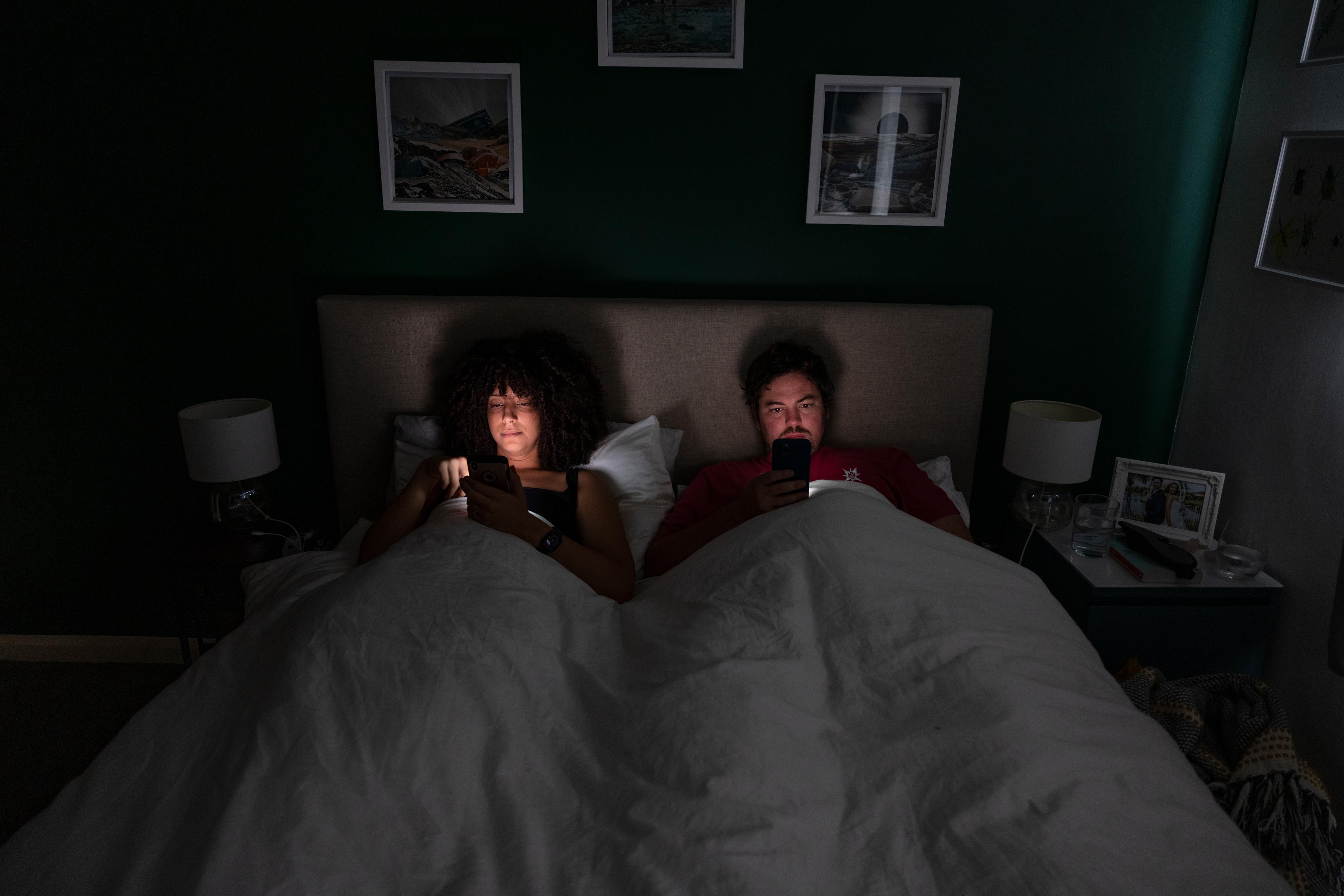 A couple in bed scrolling on their mobile phones