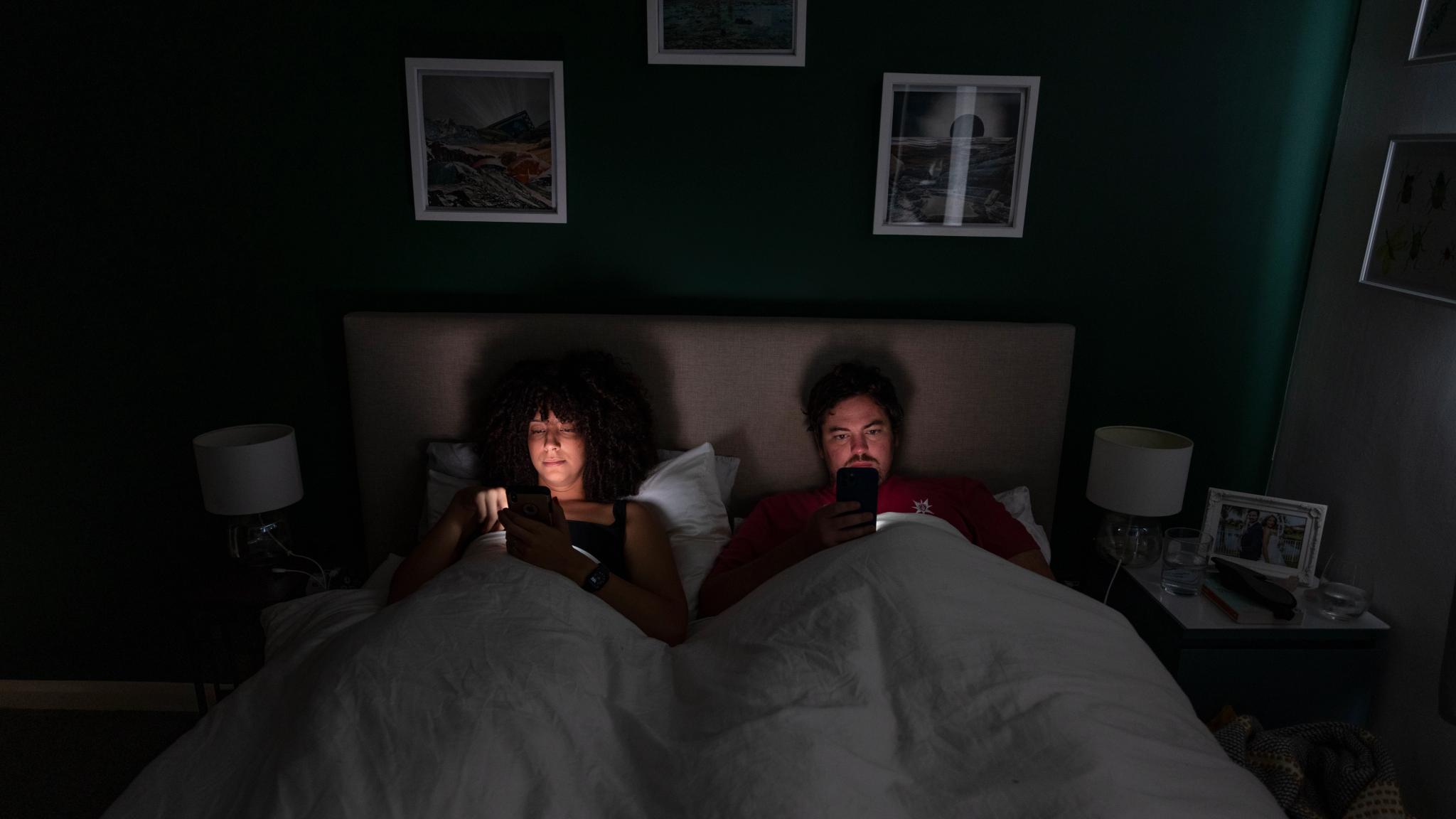 A couple in bed scrolling on their mobile phones