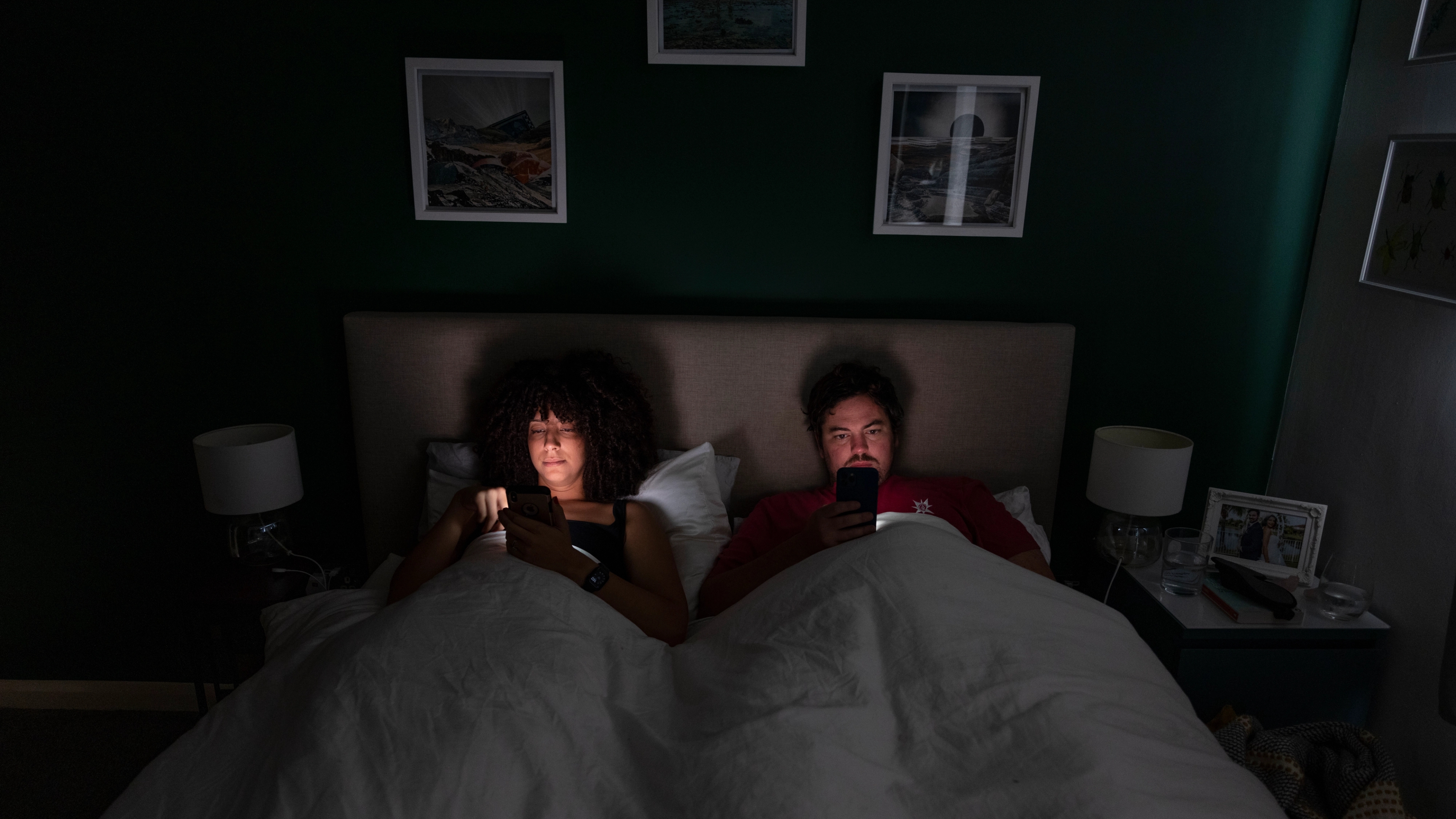A couple in bed scrolling on their mobile phones