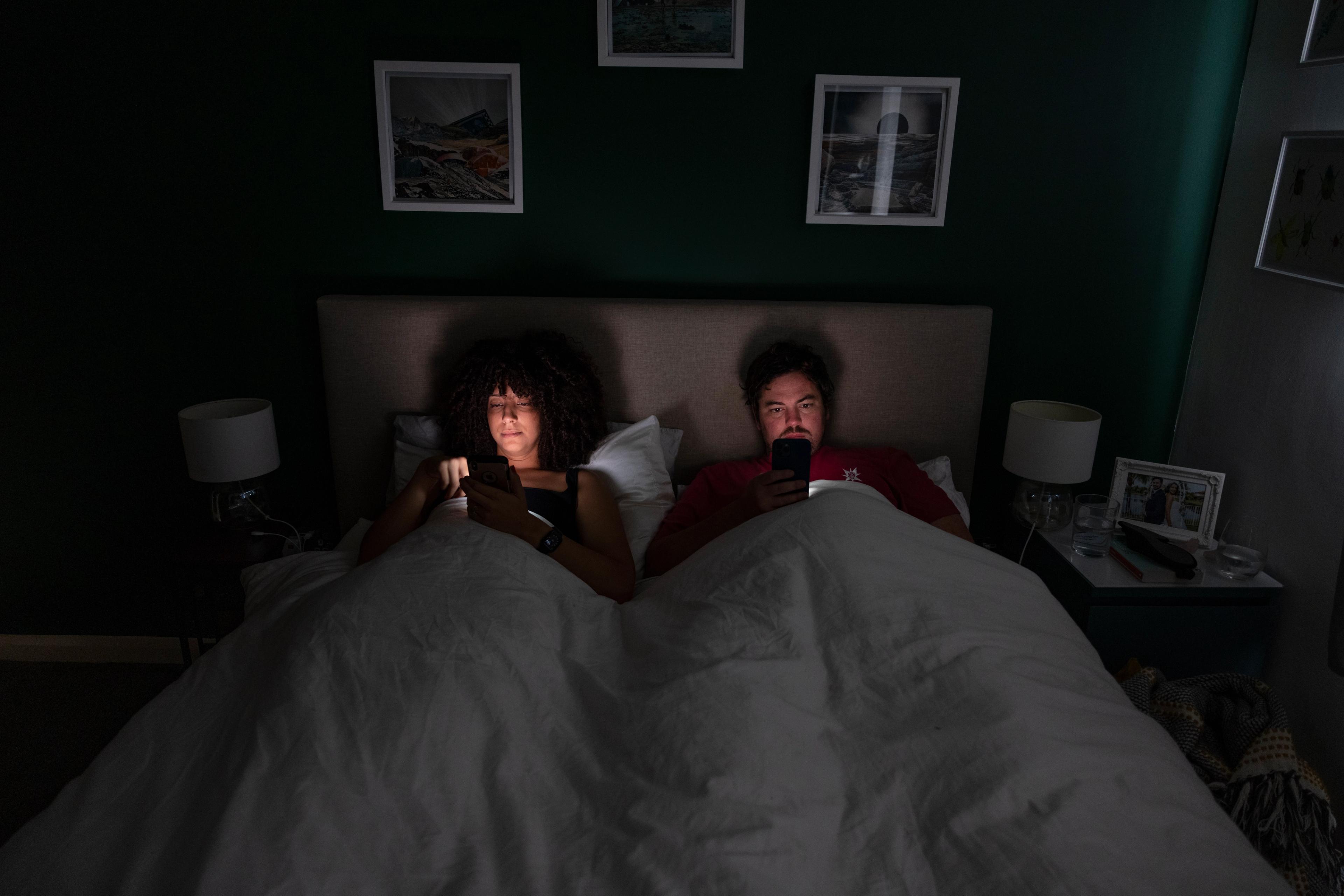 A couple in bed scrolling on their mobile phones