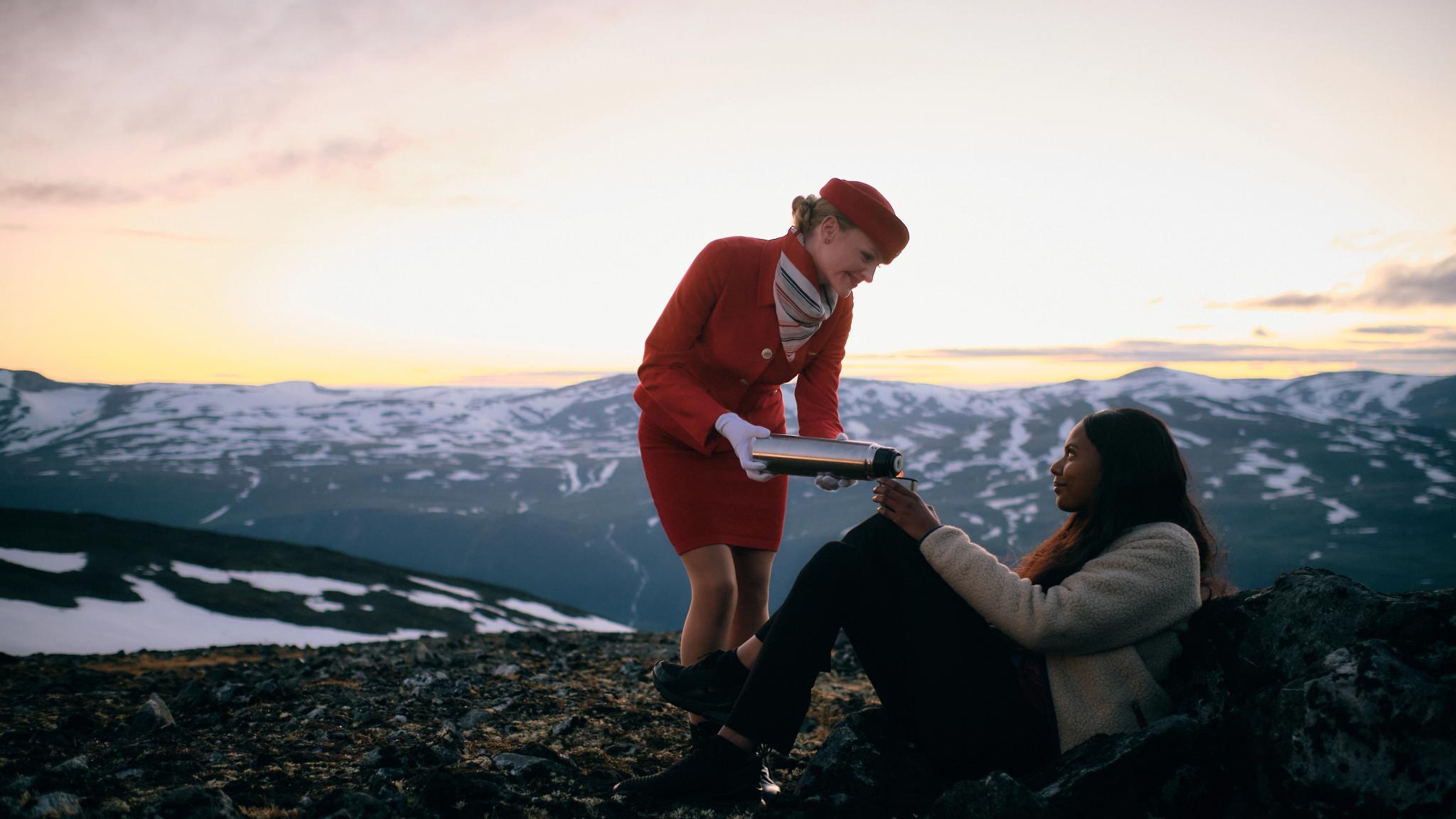 A woman being served coffee on a mountain top from a flight attendant