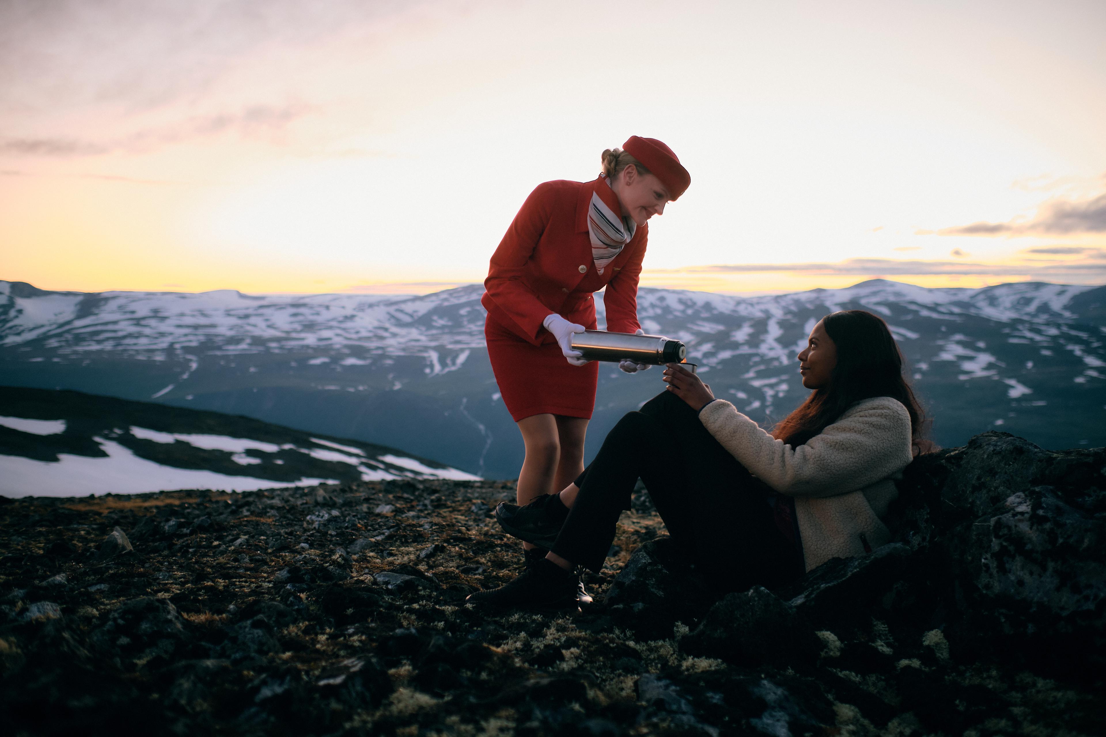 A woman being served coffee on a mountain top from a flight attendant