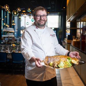 Male chef with skrei on a big plate in a restaurant