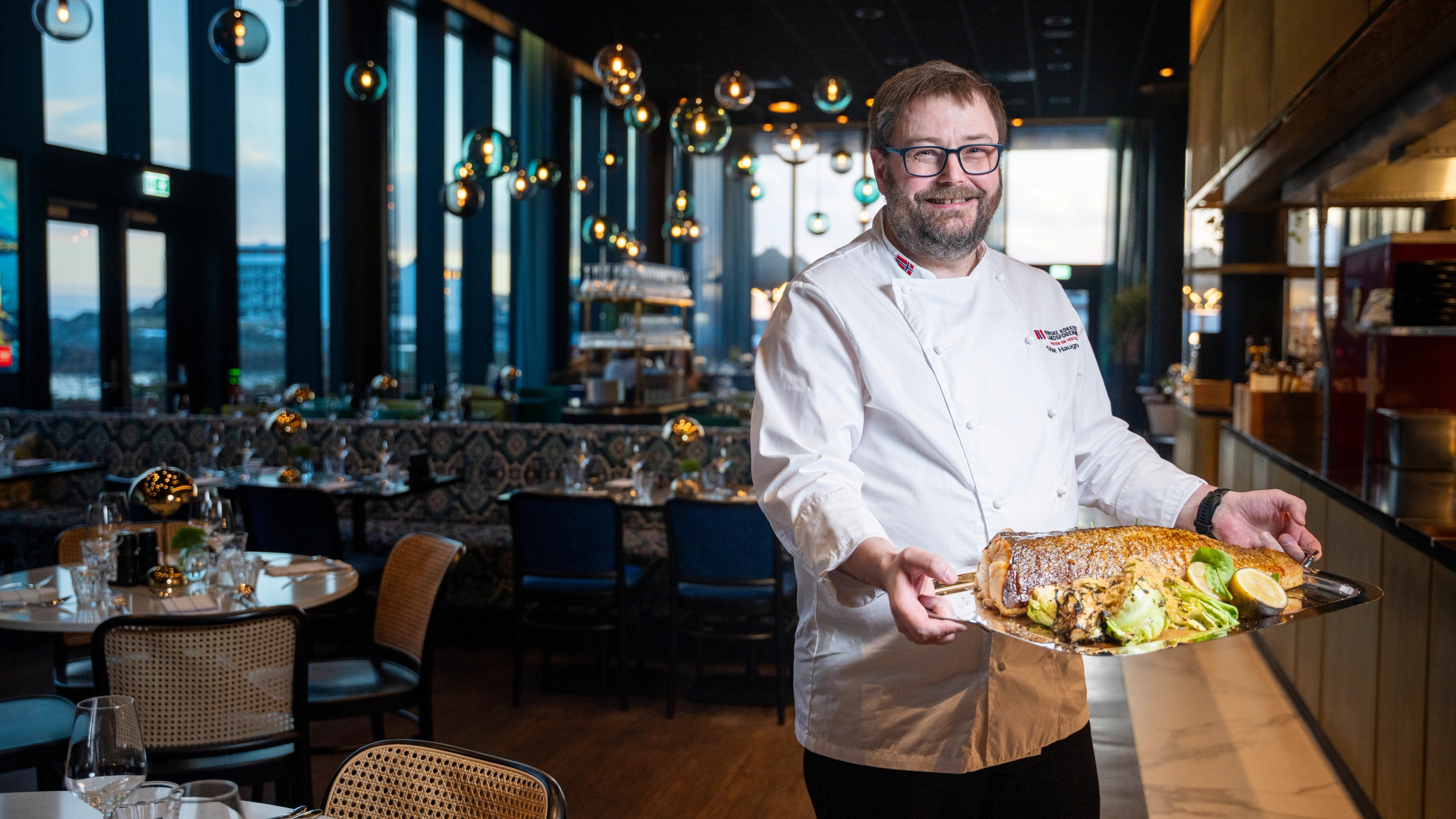 En kjøkkensjef med en skrei på en stor tallerken i en restaurant