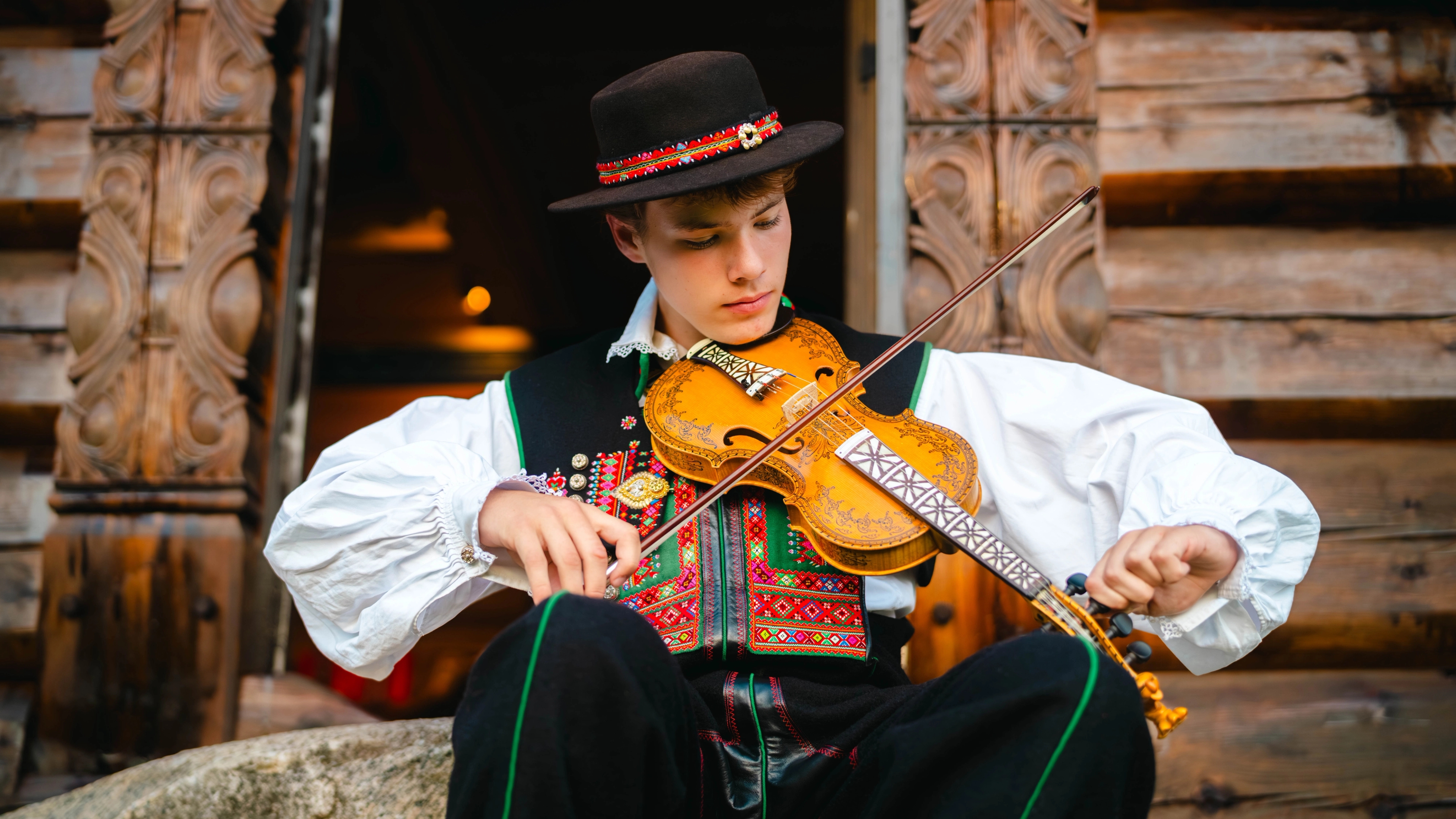 A young man from Setesdal playing the hardingfele (Hardanger fiddle), adorned with intricate decorations.