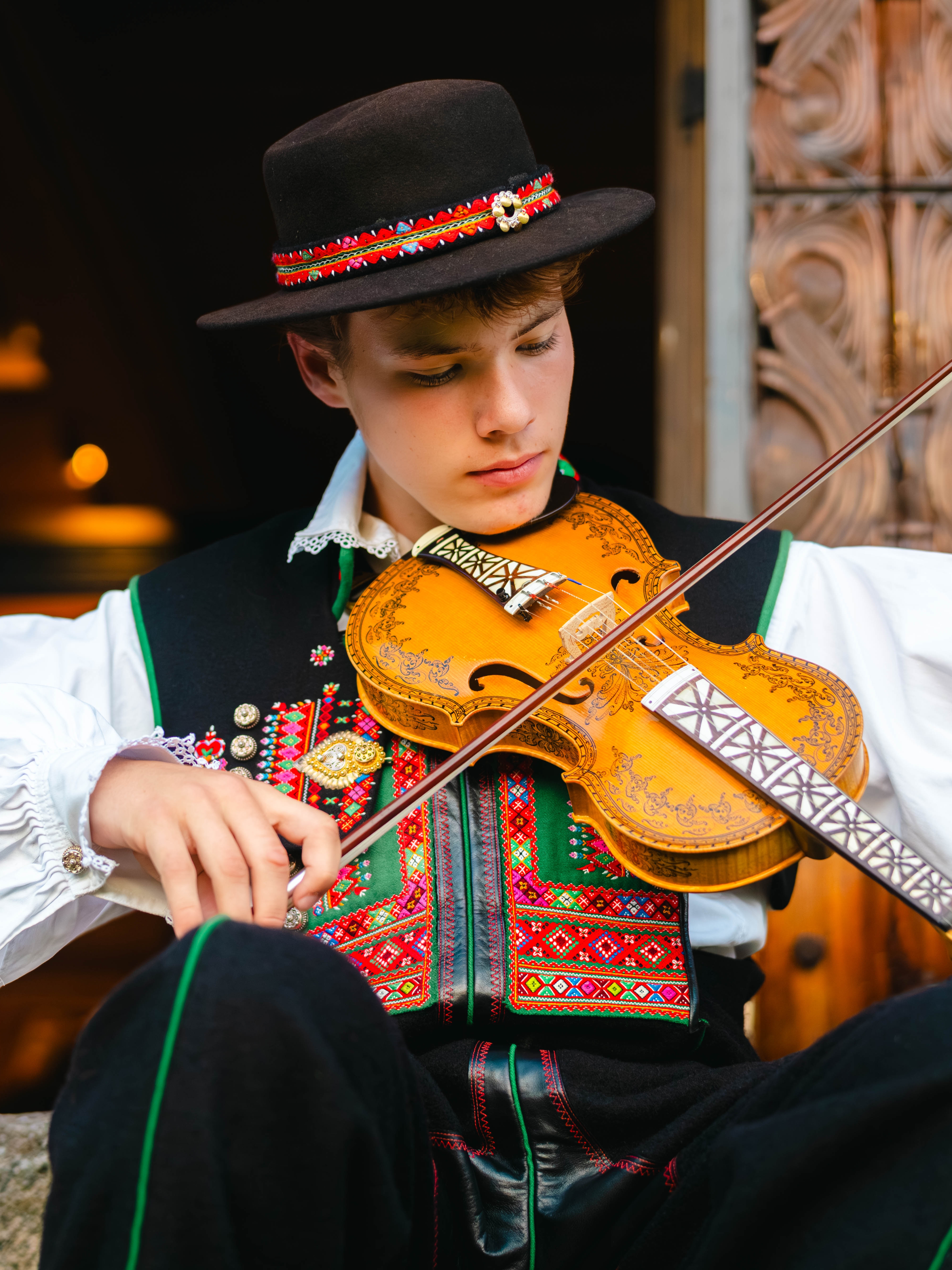 A young man from Setesdal playing the hardingfele (Hardanger fiddle), adorned with intricate decorations.