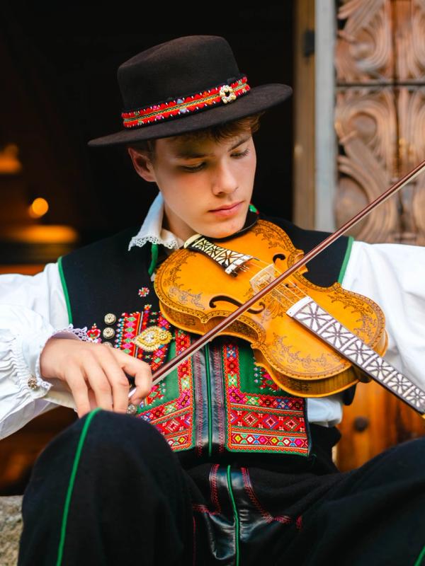 A young man from Setesdal playing the hardingfele (Hardanger fiddle), adorned with intricate decorations.